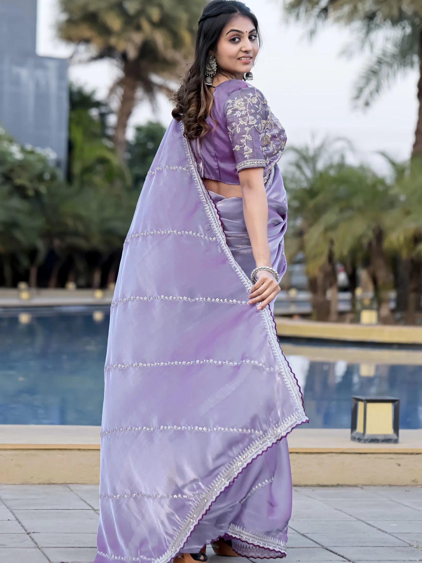 Woman in a lavender saree with a blurred outdoor background