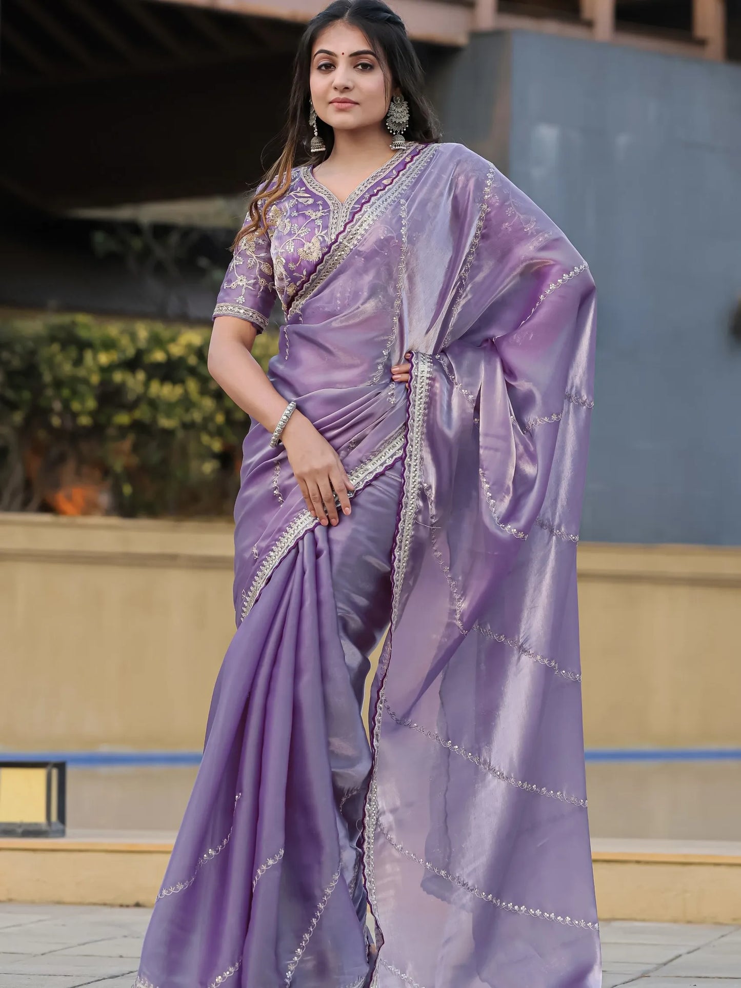 Woman wearing a purple saree with a matching blouse outdoors.