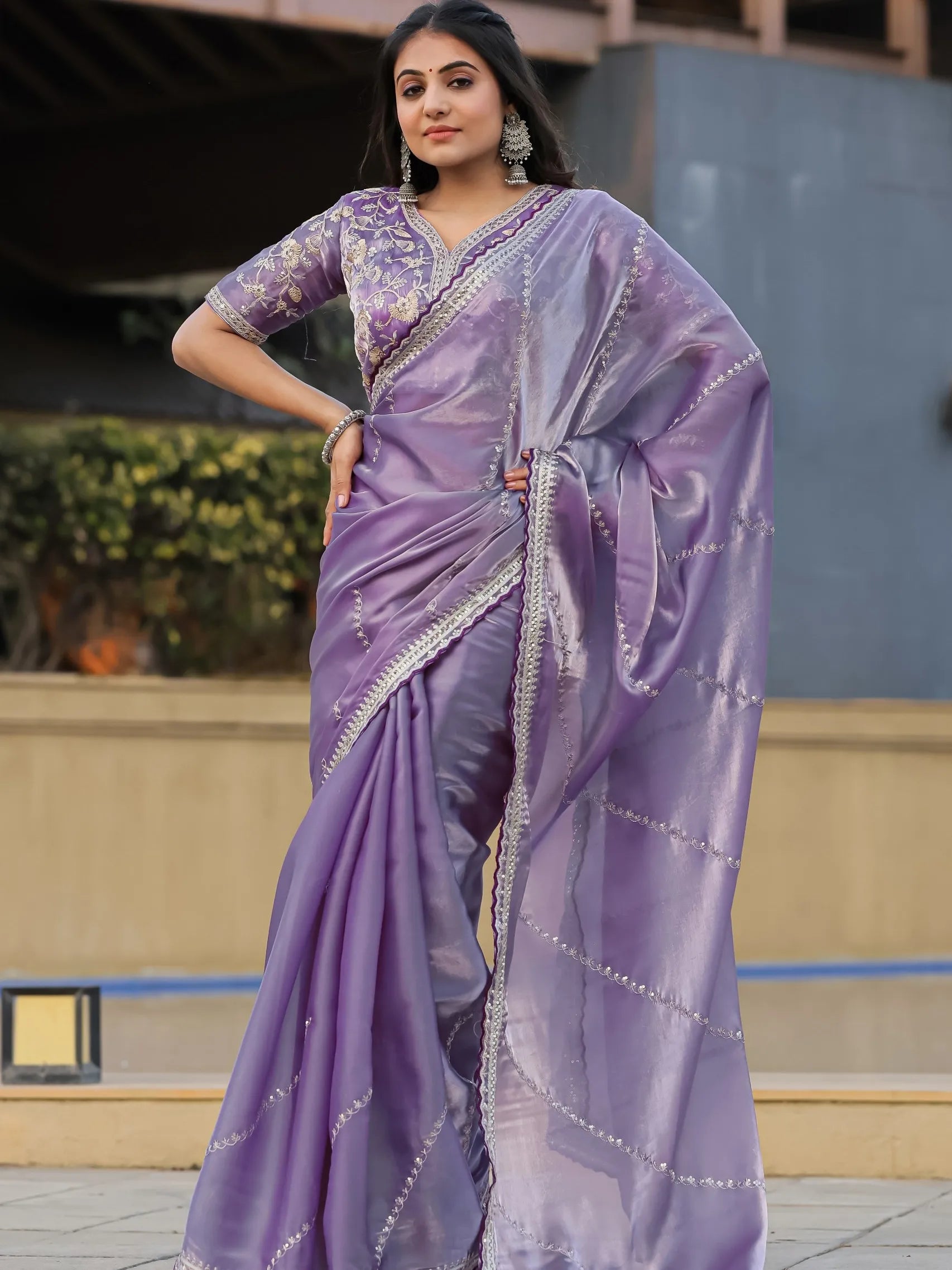 Woman wearing a purple saree with silver embroidery in an outdoor setting