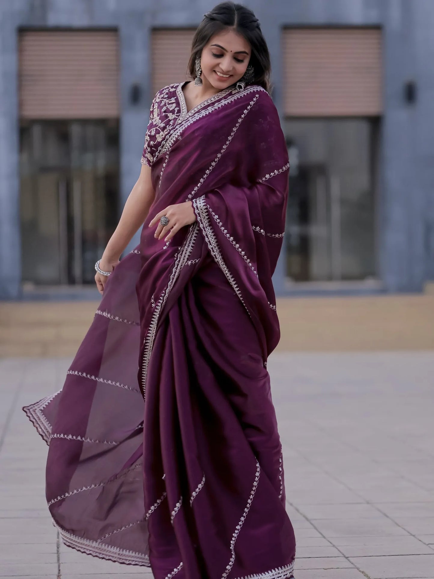 Woman wearing a purple saree with white patterns outdoors.