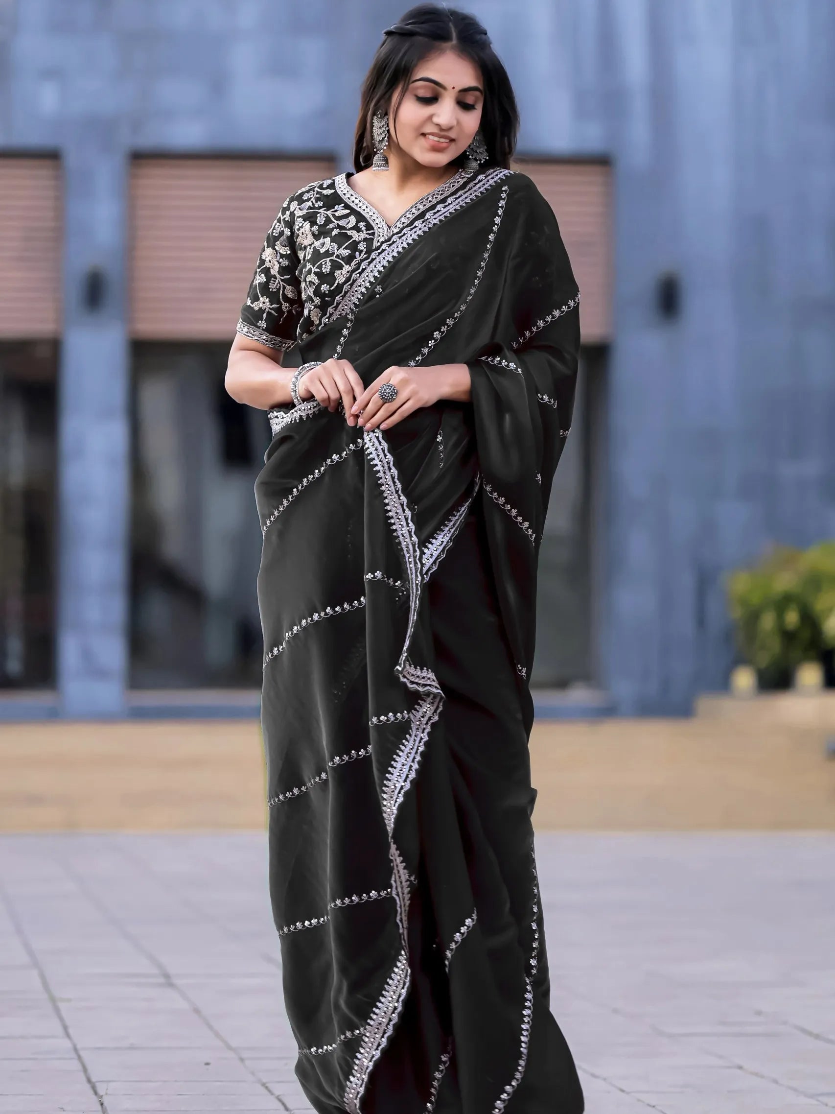 Woman wearing a black saree with white patterns outdoors.