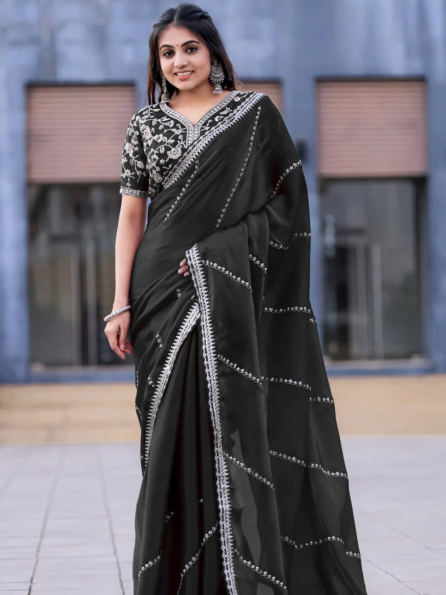 Woman wearing a black saree with white patterns in an outdoor setting