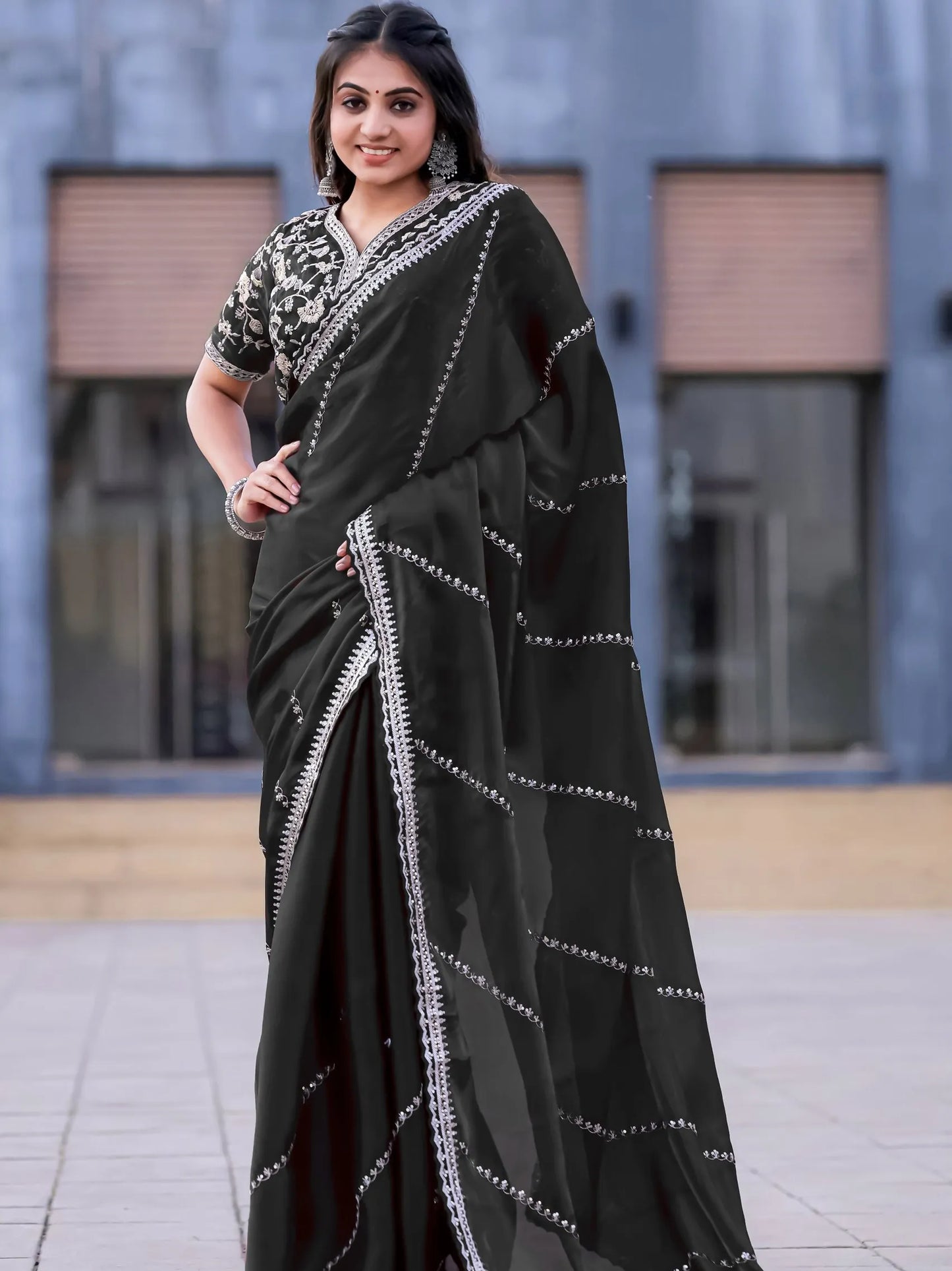 Woman wearing a black saree with white patterns in an outdoor setting
