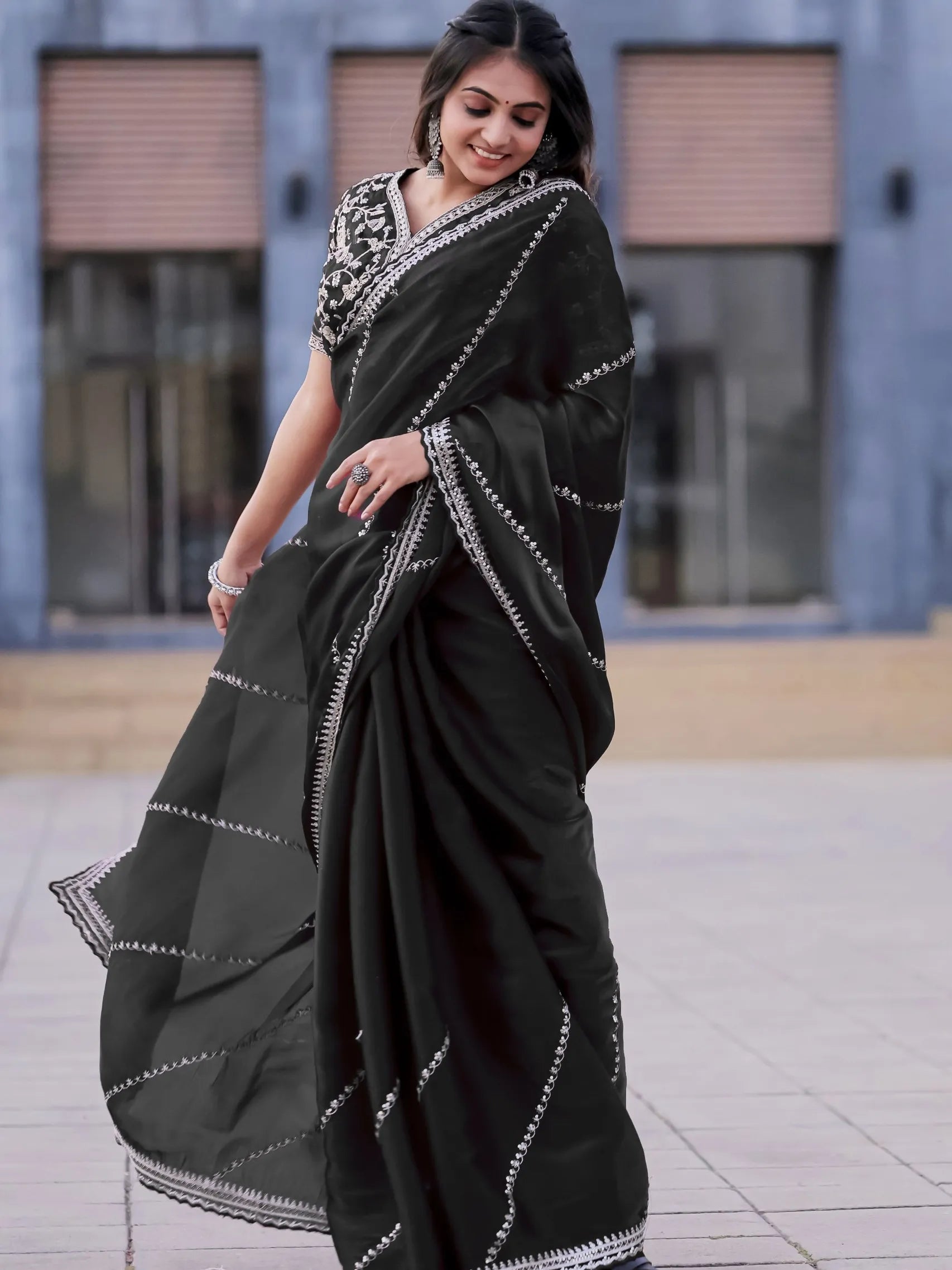 Woman wearing a black saree with white patterns outdoors.