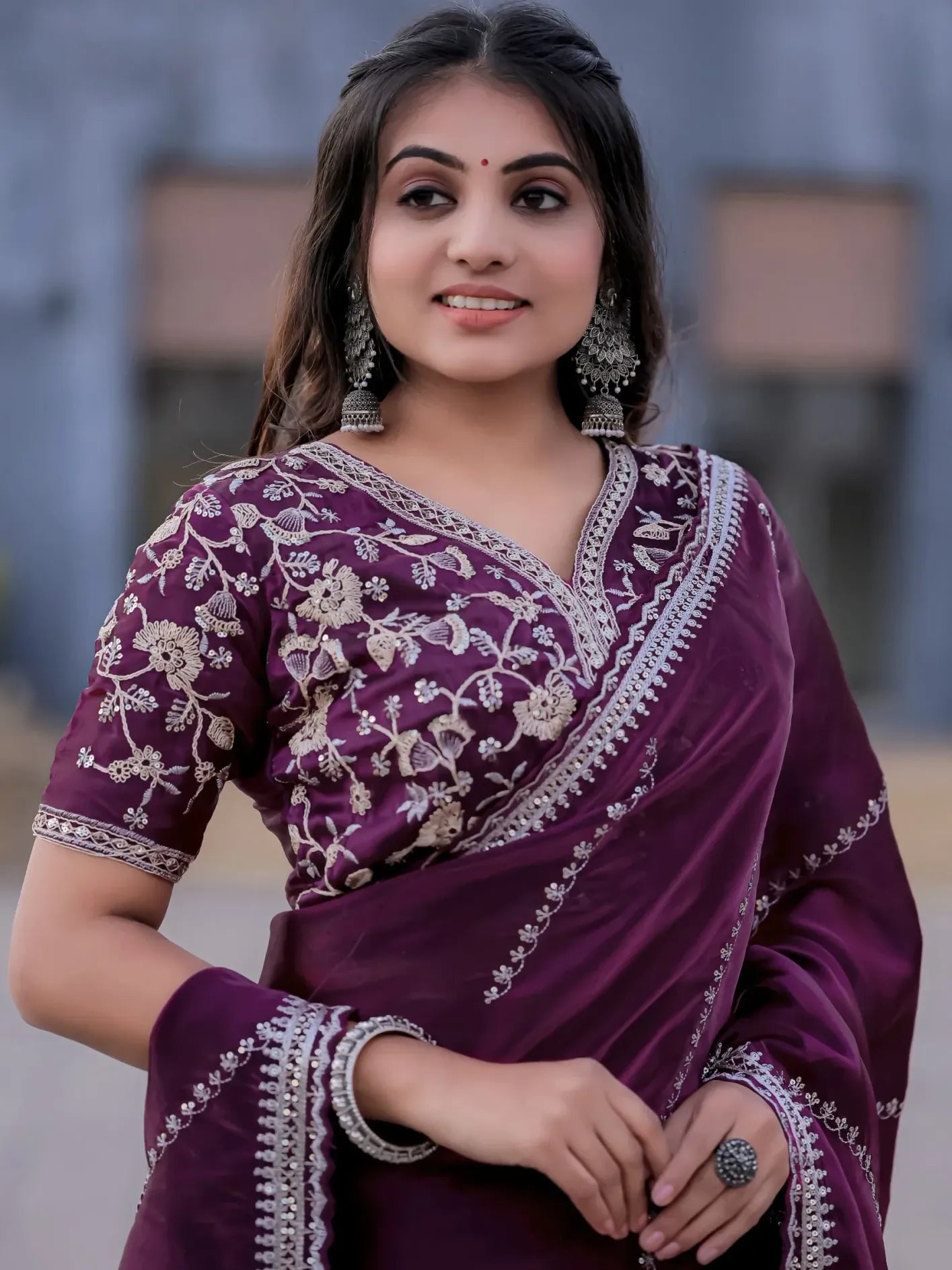 Woman wearing a purple saree with white embroidery against a blurred background