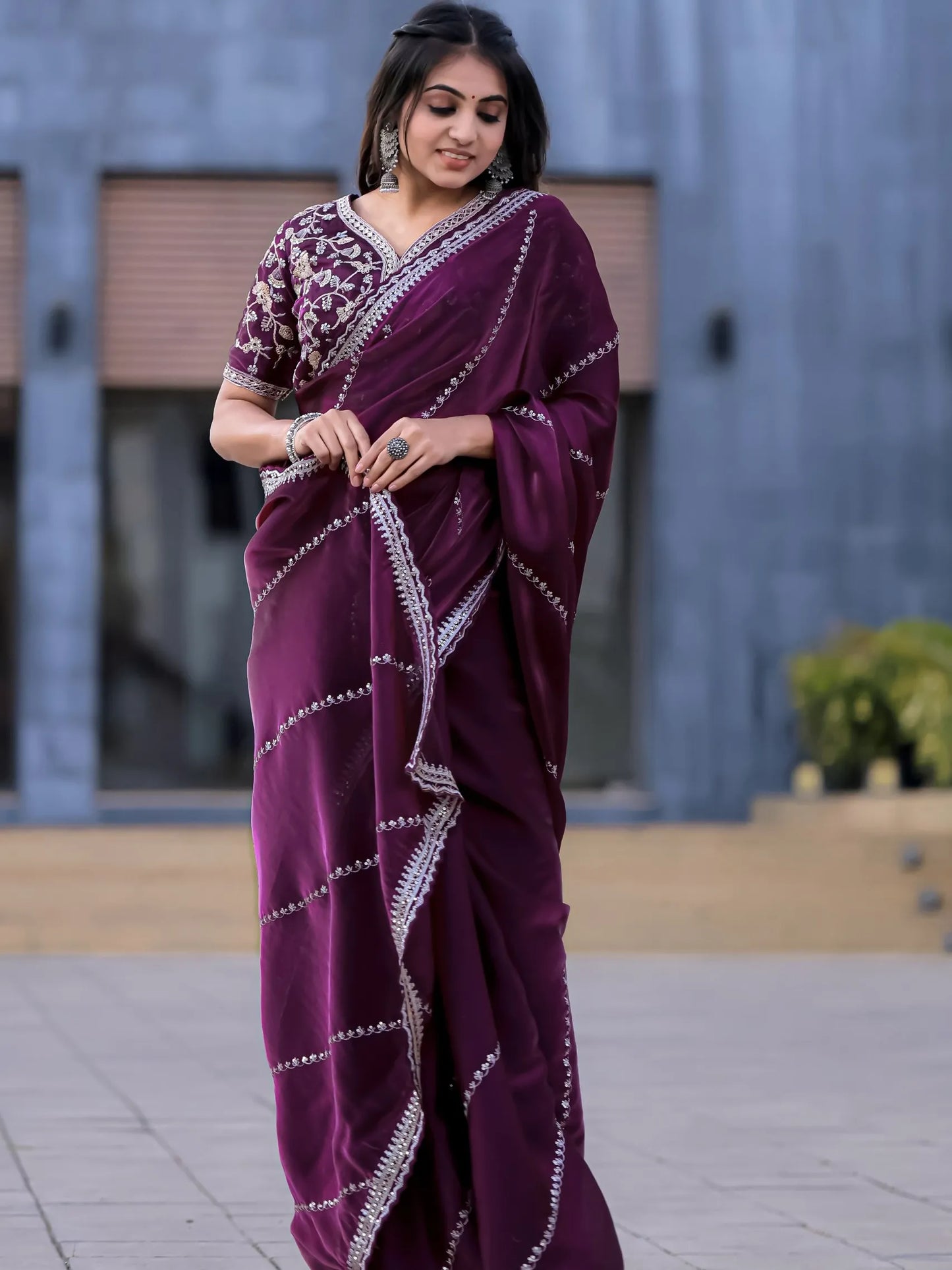 Woman wearing a purple saree with white patterns outdoors.