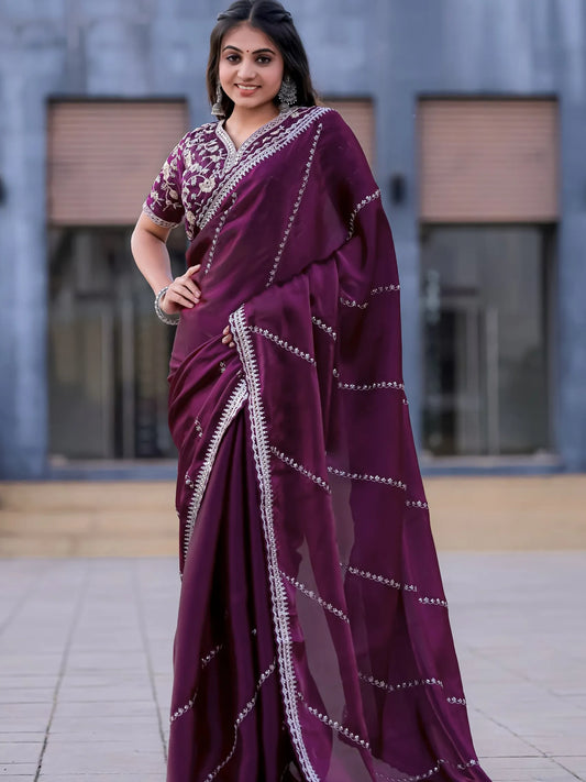 Woman wearing a purple saree with white patterns in an outdoor setting