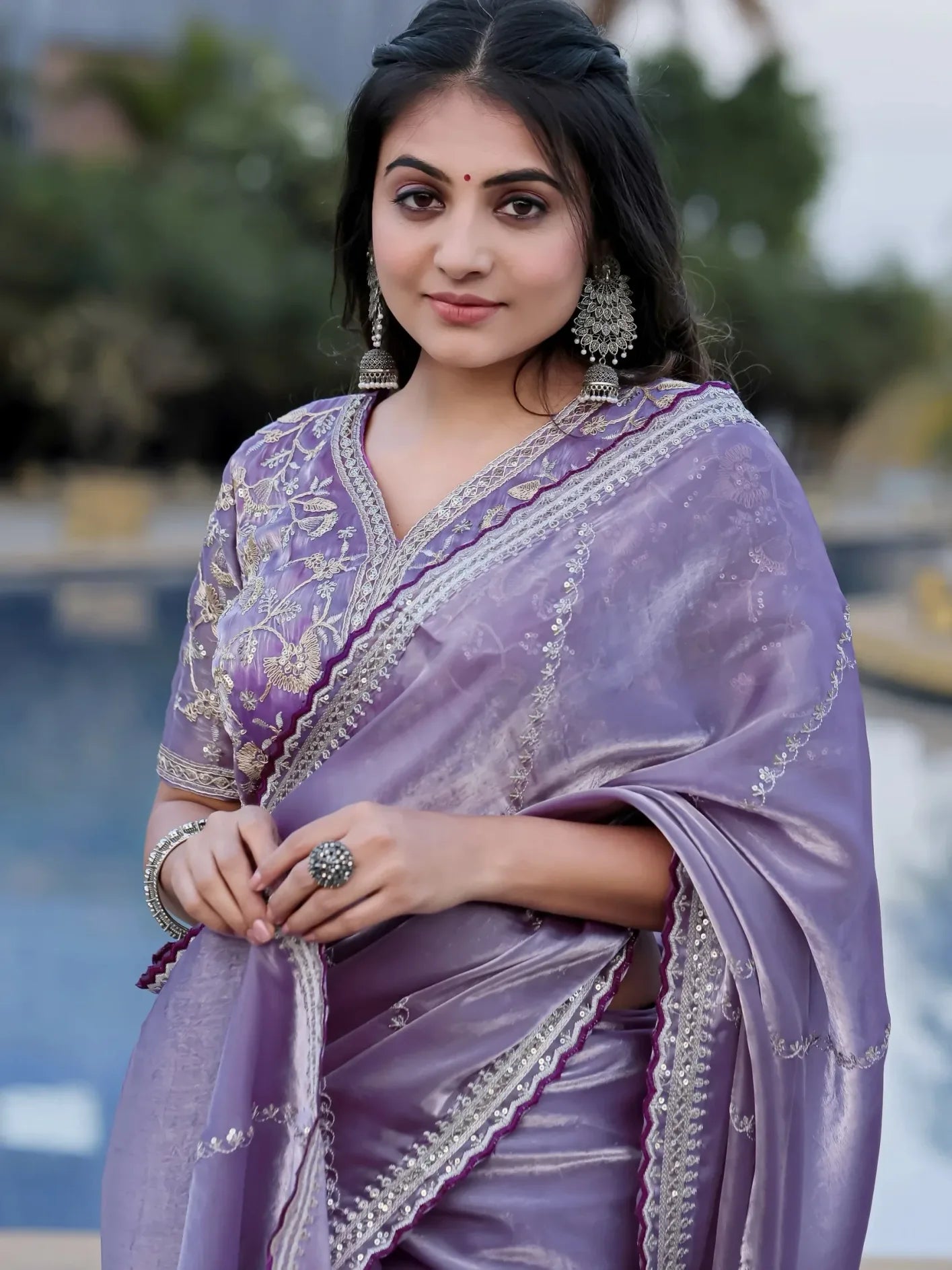 Woman wearing a purple saree with intricate designs outdoors
