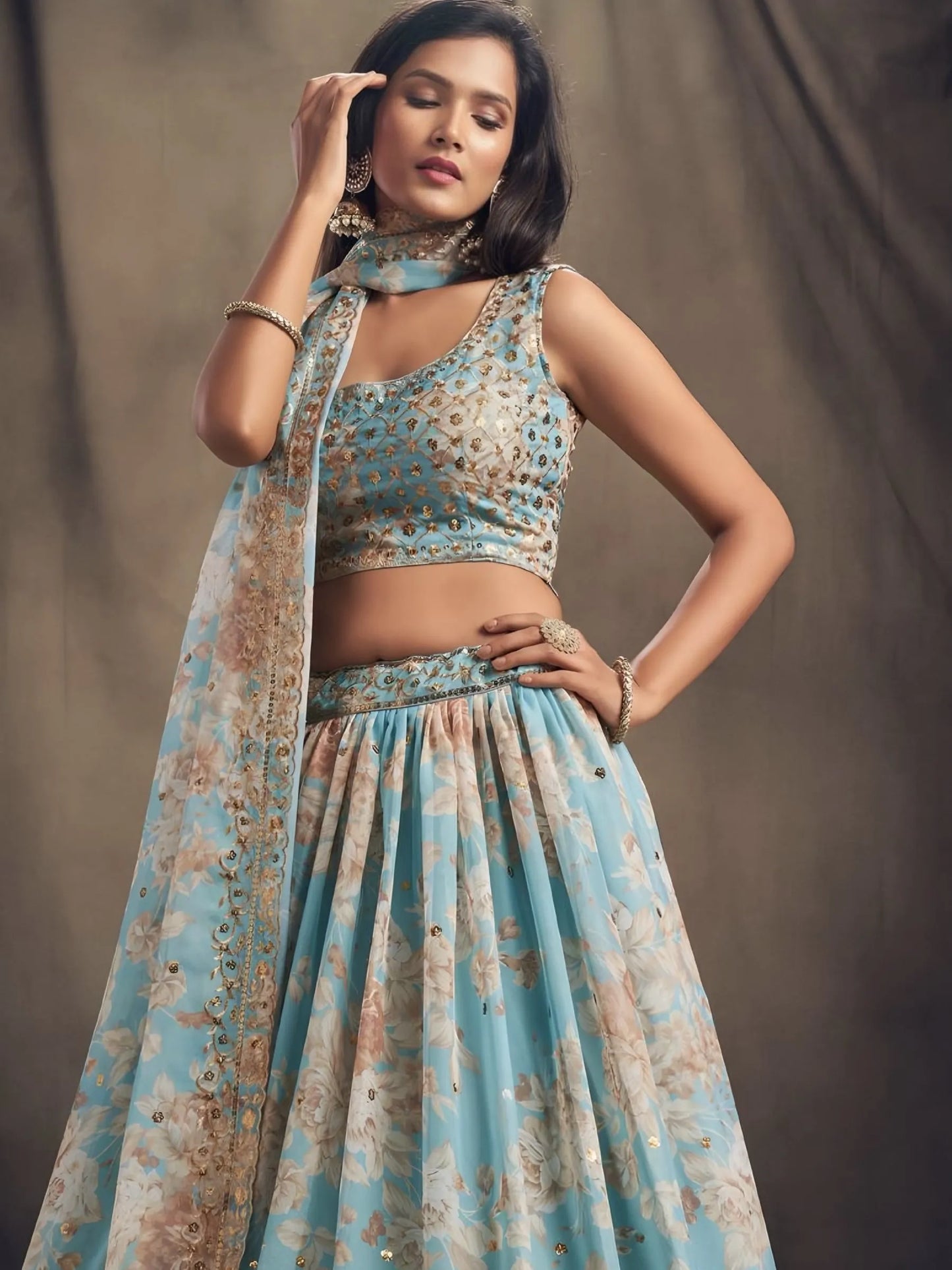 Woman wearing a floral dress with a matching dupatta against a plain background