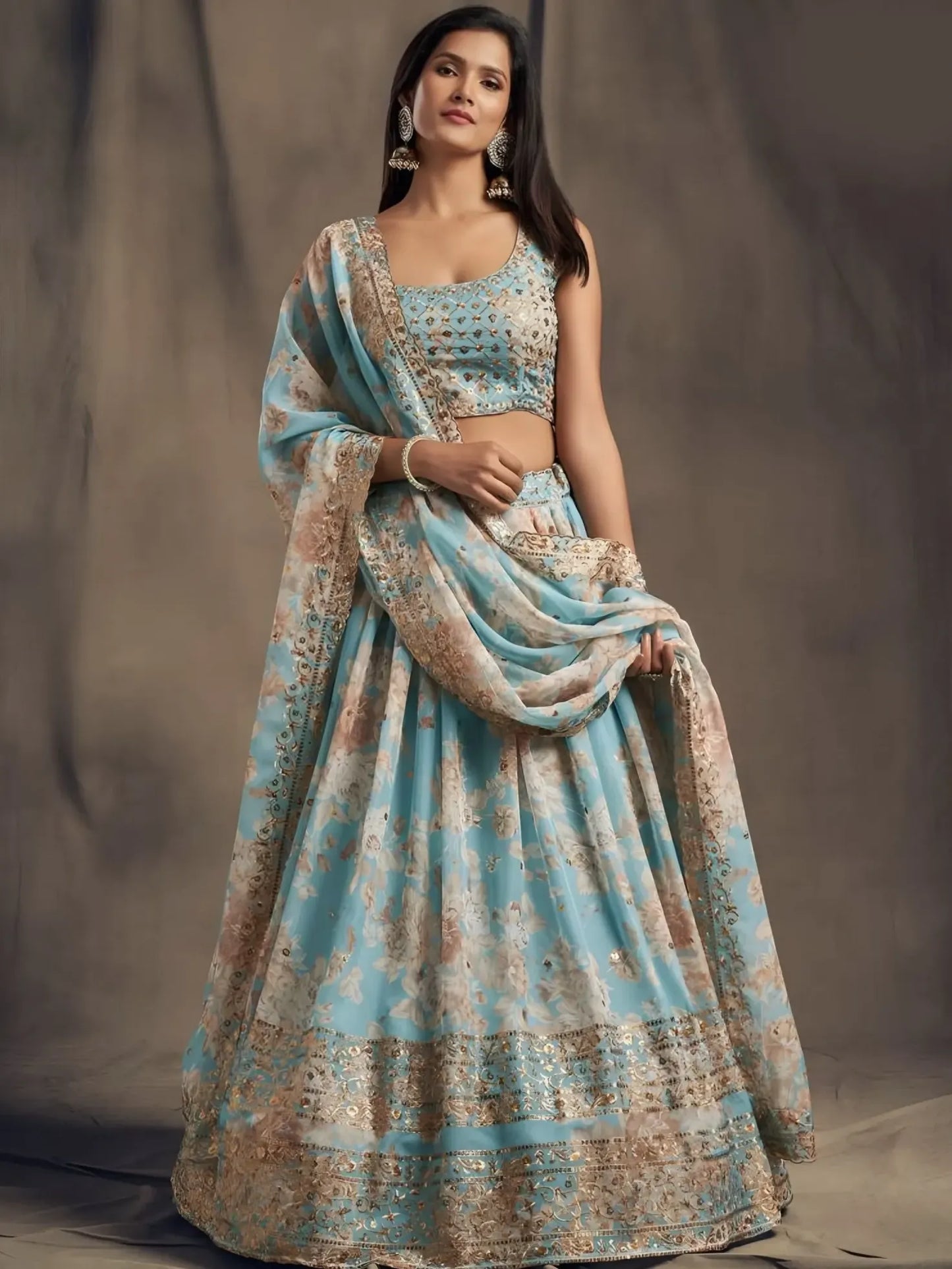 Woman wearing a traditional blue and beige saree with a matching blouse against a neutral background
