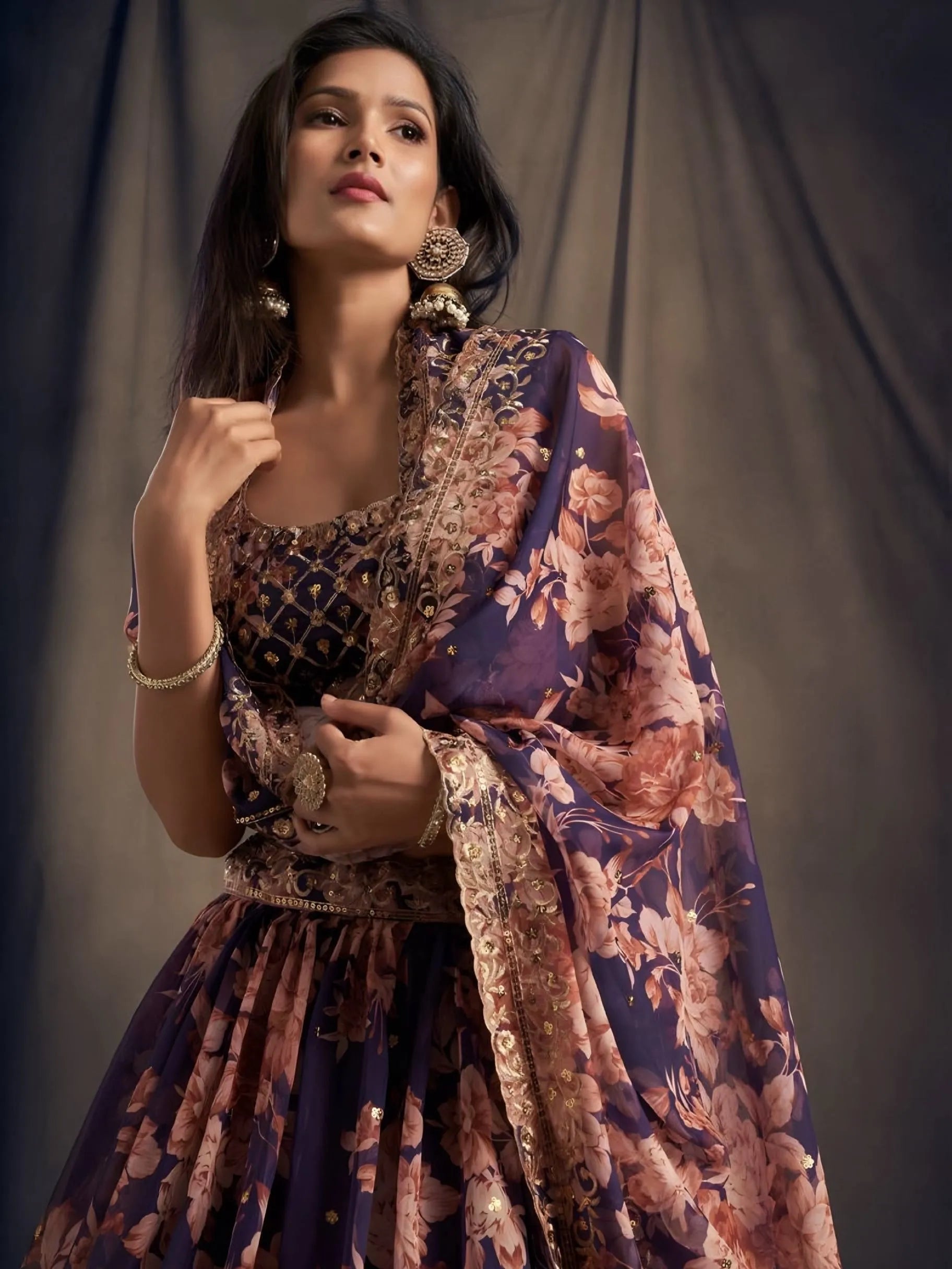 Woman wearing a floral dress and shawl against a plain background