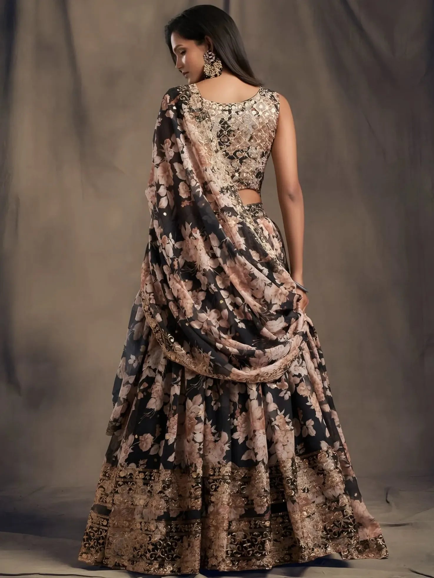 Woman wearing a floral saree with a draped design against a plain background