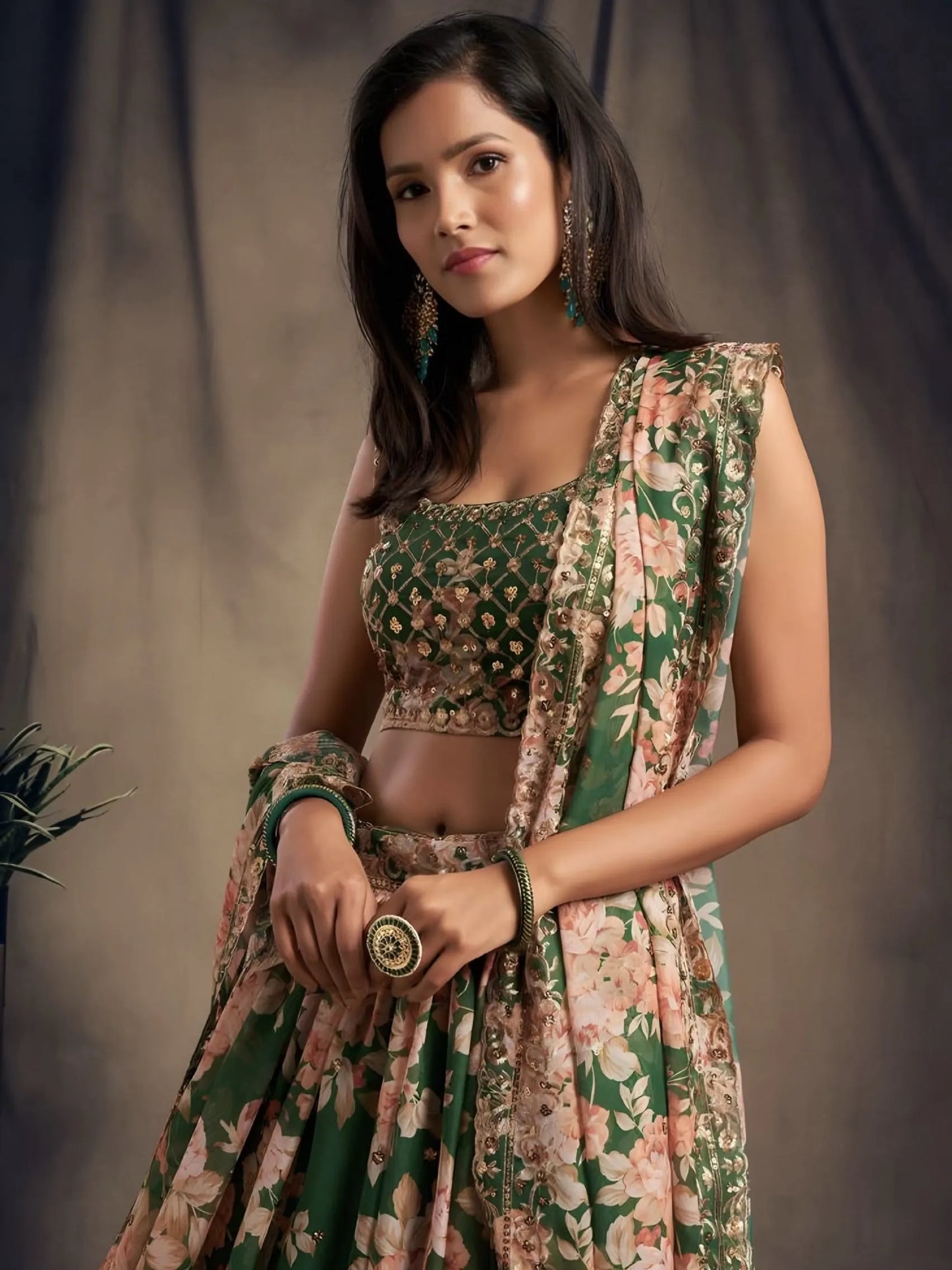 Woman wearing a floral and green traditional outfit against a plain background