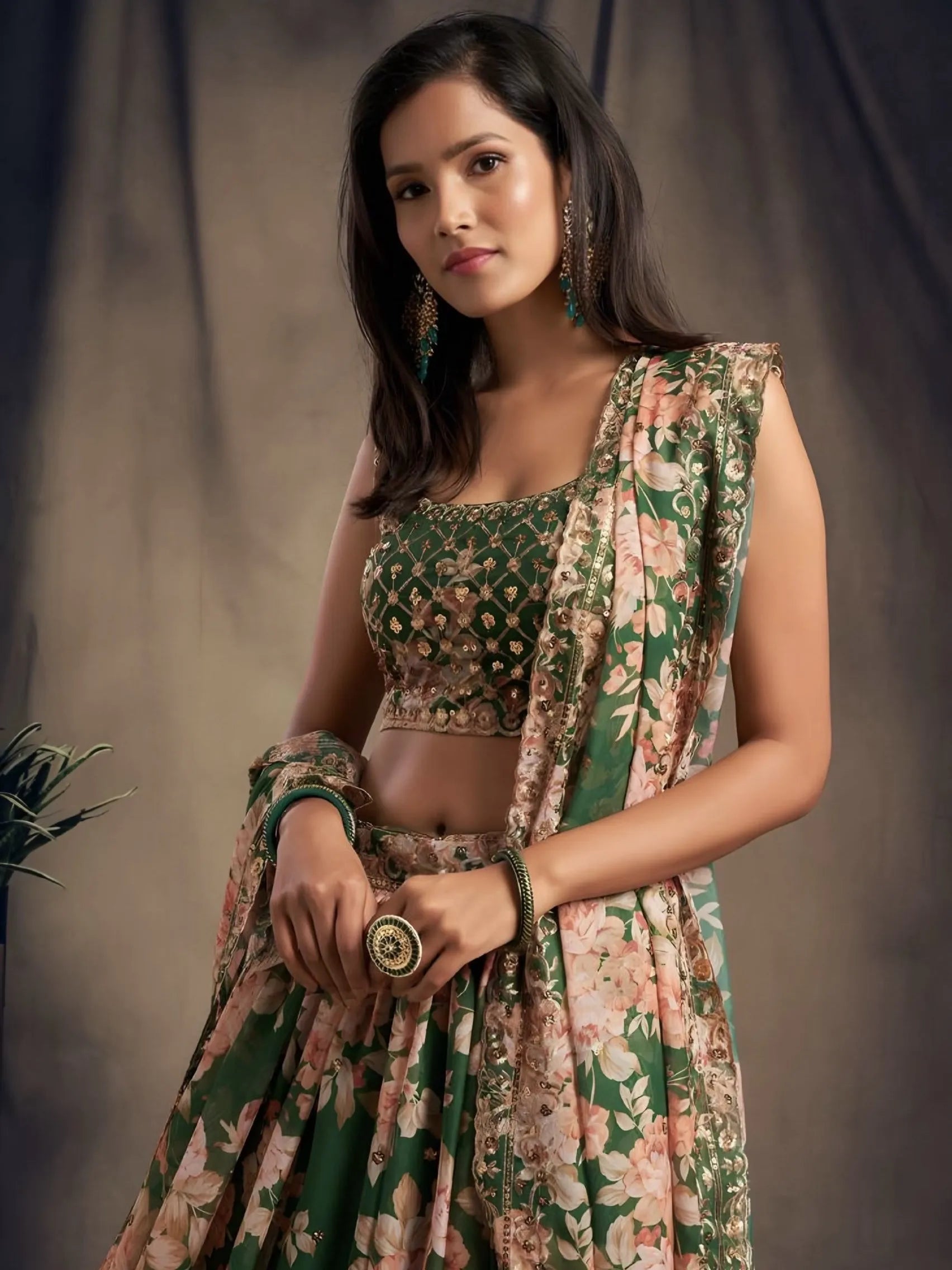 Woman wearing a floral and green traditional outfit against a plain background