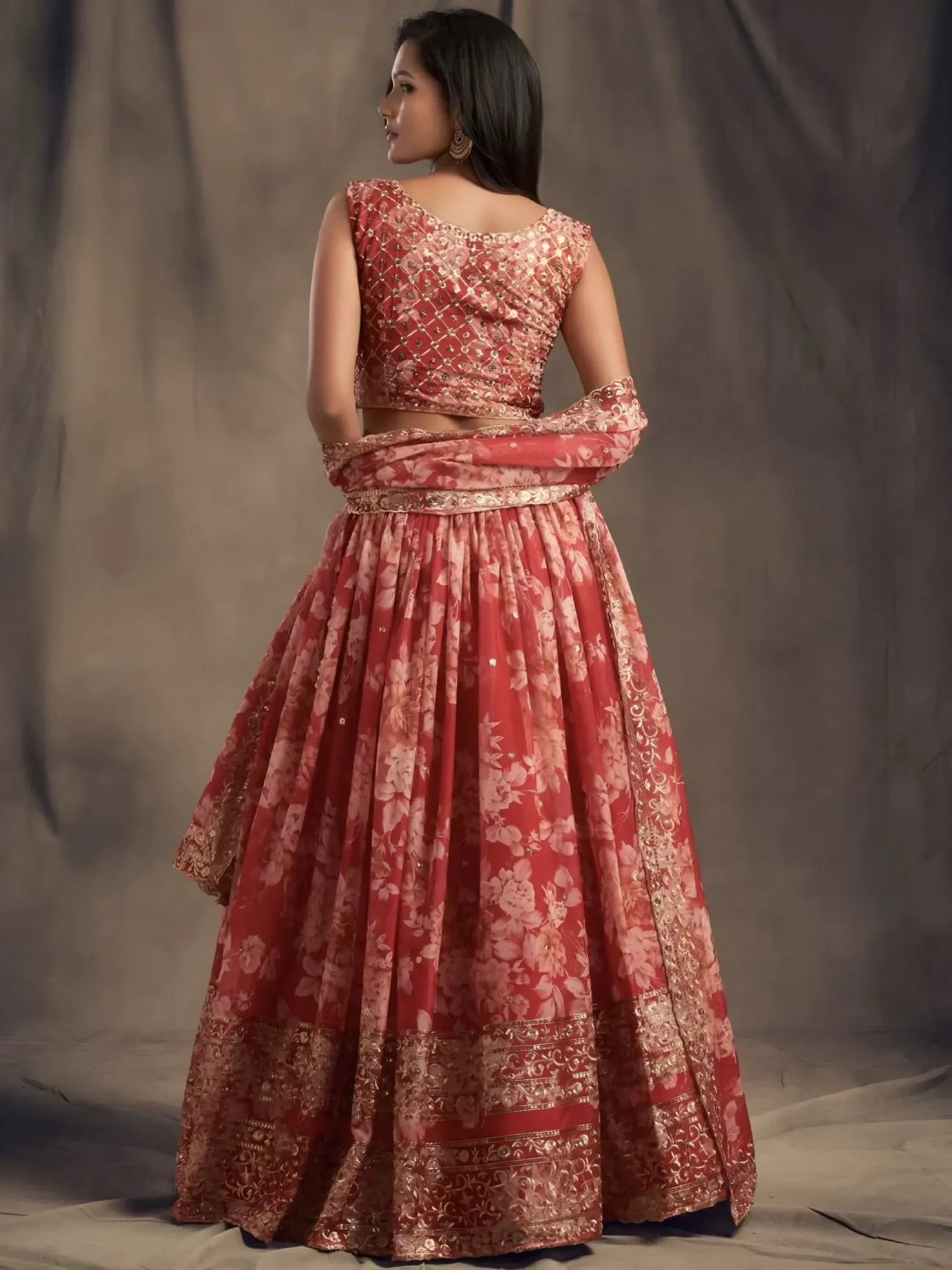 Woman wearing a red and gold traditional outfit against a plain background