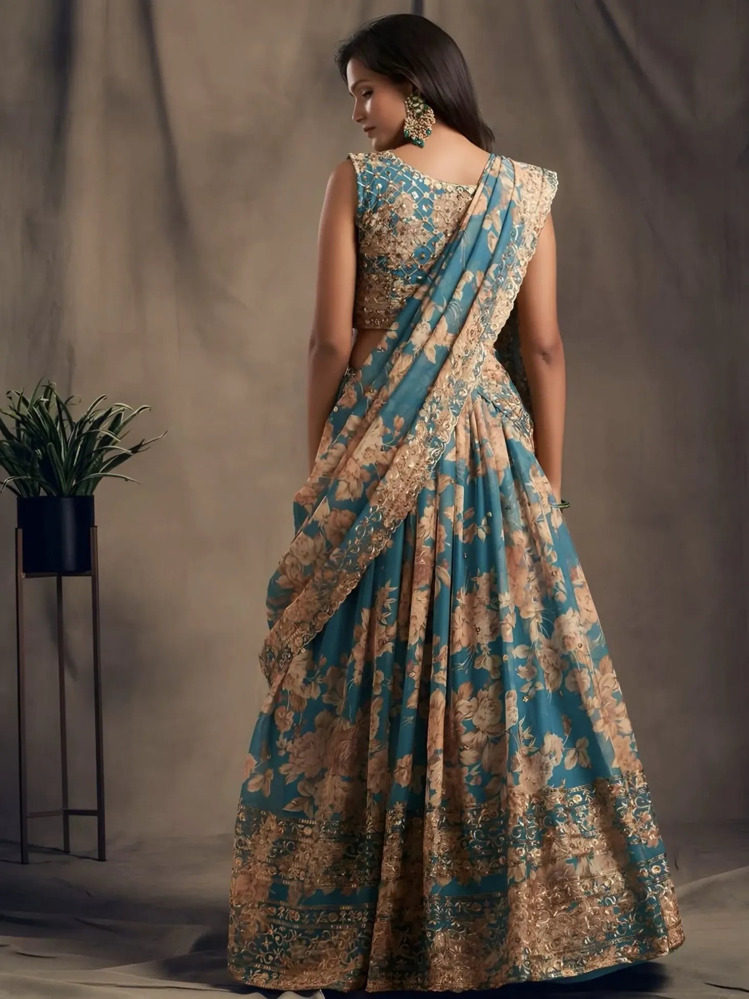 Woman wearing a floral saree with a blue and beige pattern against a plain background