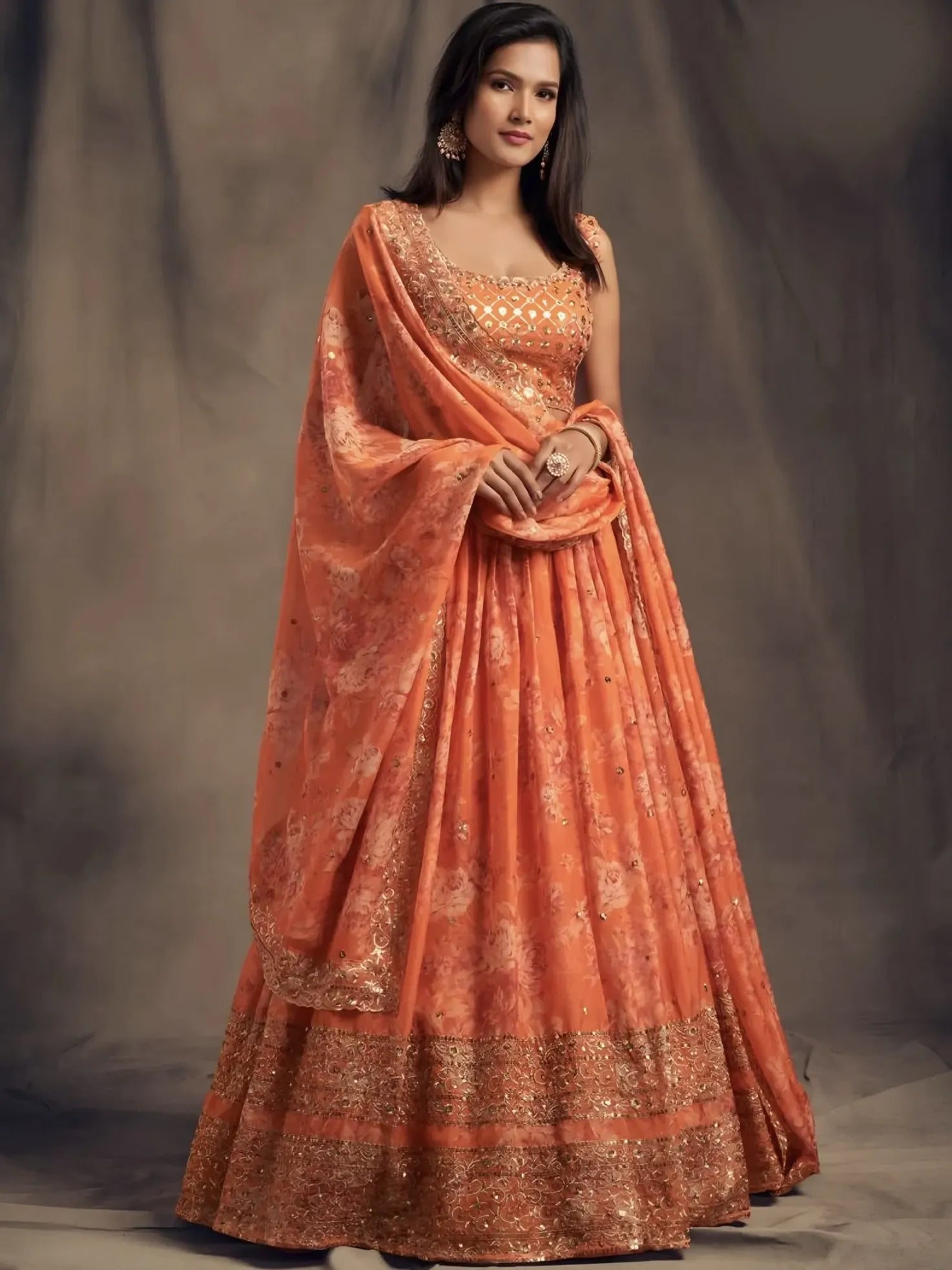 Woman wearing an orange saree with a plain background