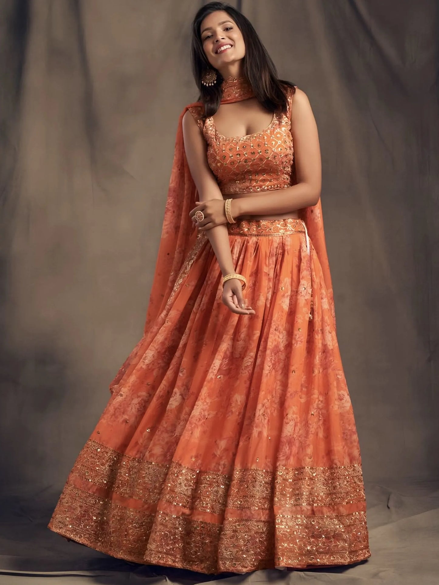 Woman wearing an orange traditional outfit with a plain background