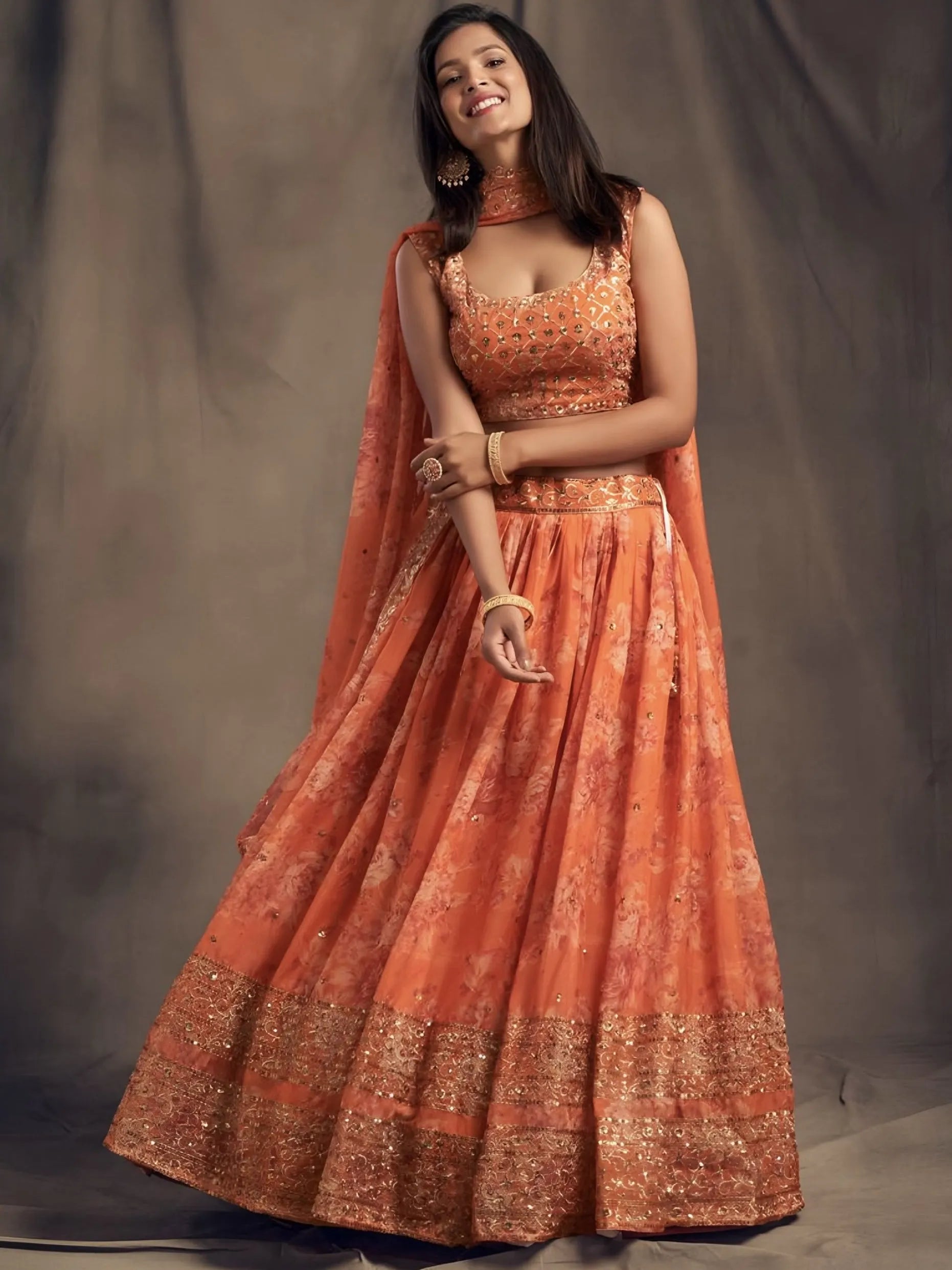 Woman wearing an orange traditional outfit with a plain background
