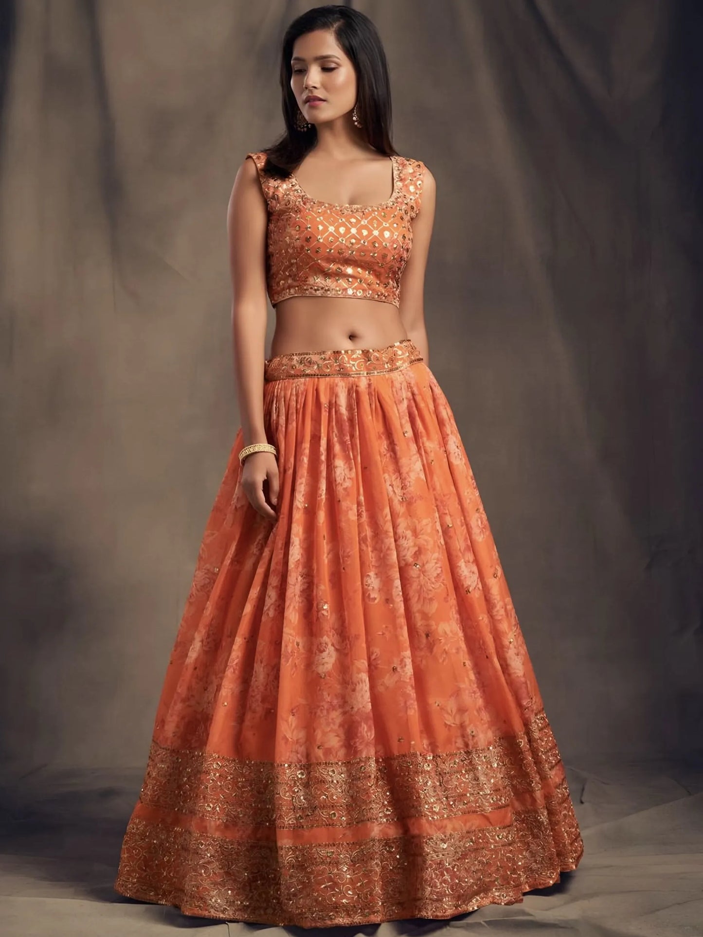 Woman wearing an orange traditional outfit with a plain background