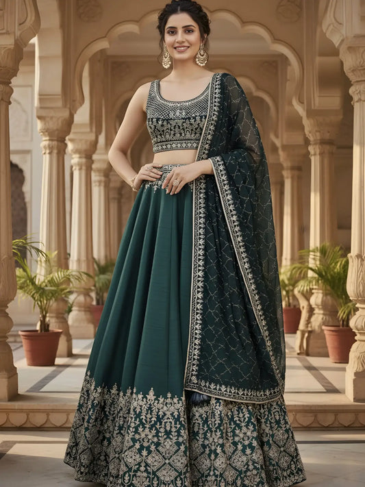 Woman in a traditional green and silver embroidered outfit standing in an architectural setting.