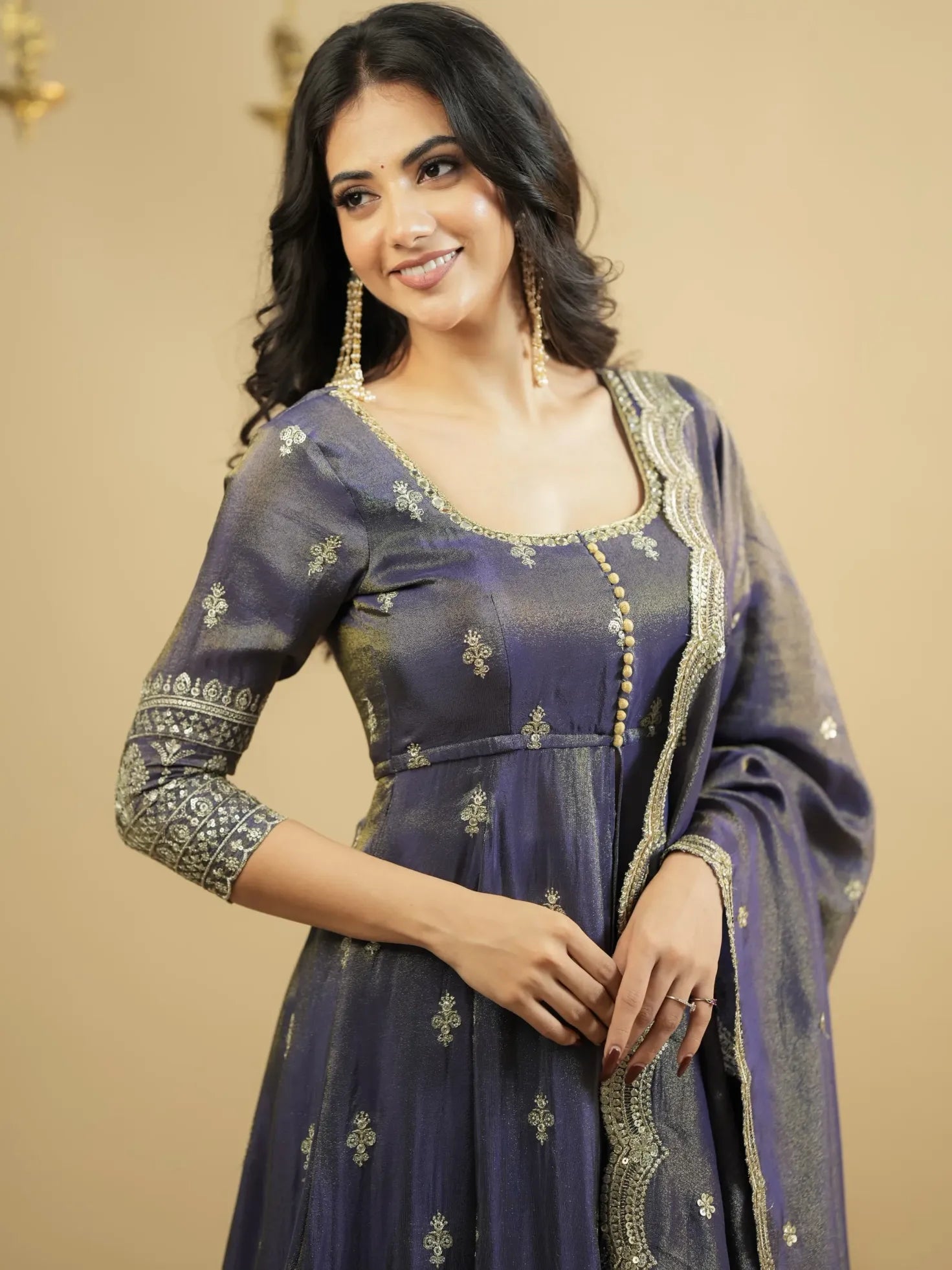 Woman wearing a traditional outfit with intricate designs on a beige background