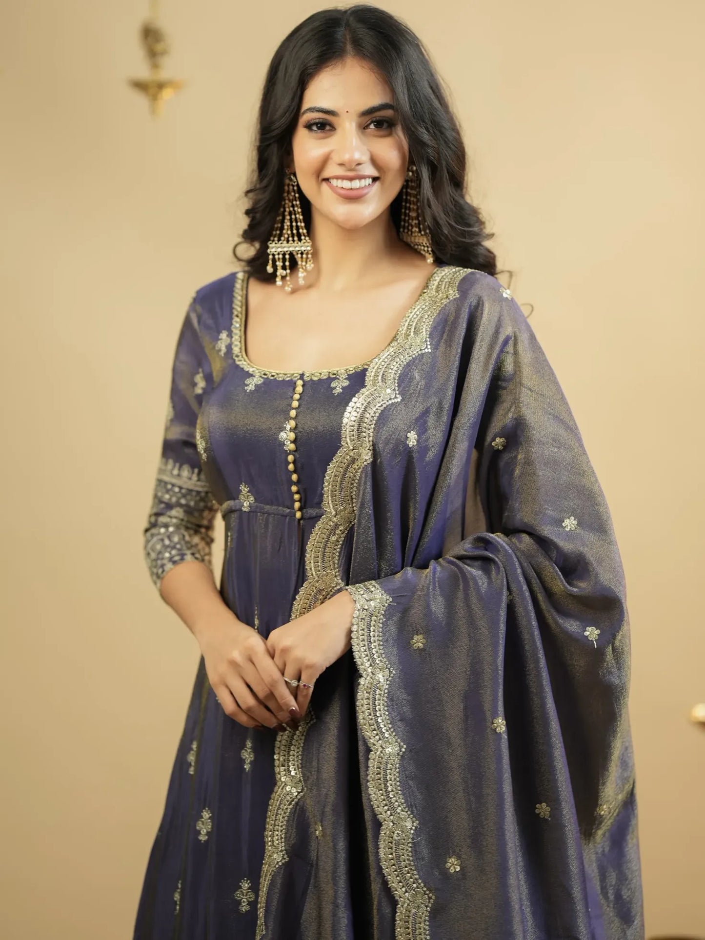 Woman wearing a traditional outfit with intricate designs on a beige background