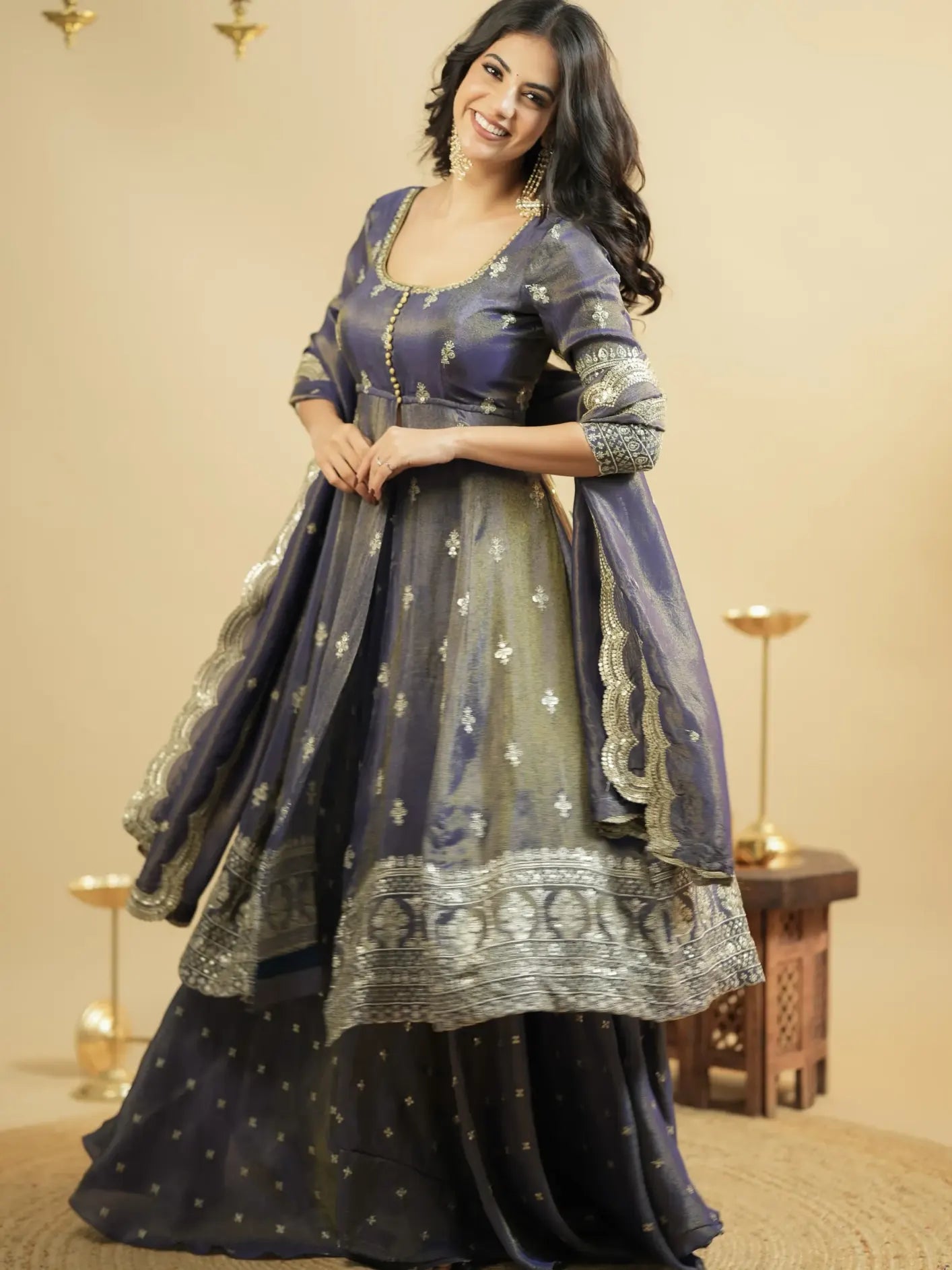 Woman wearing a traditional outfit with a dark blue and gold dress against a beige background