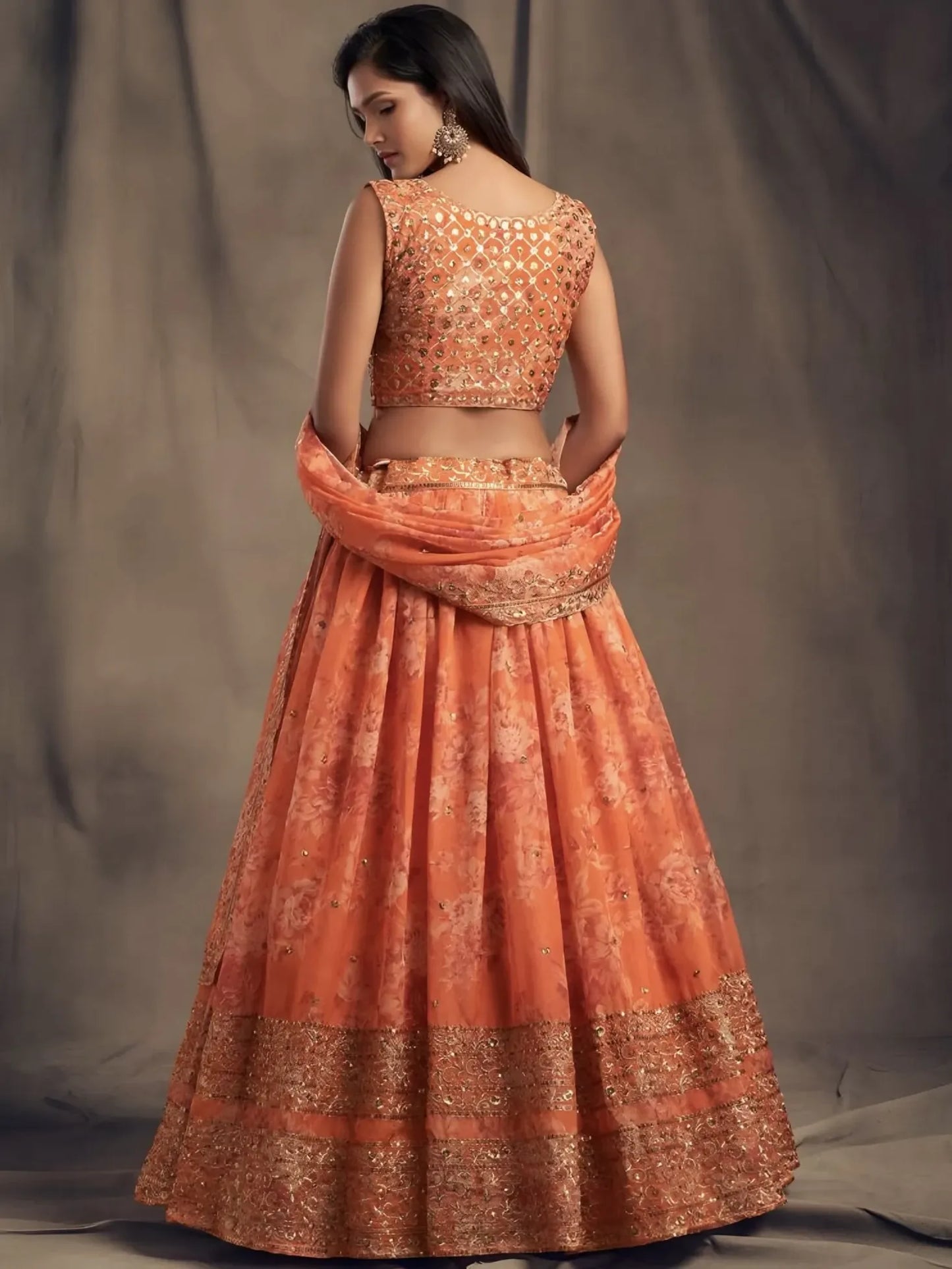 Woman wearing an orange traditional outfit with a plain background