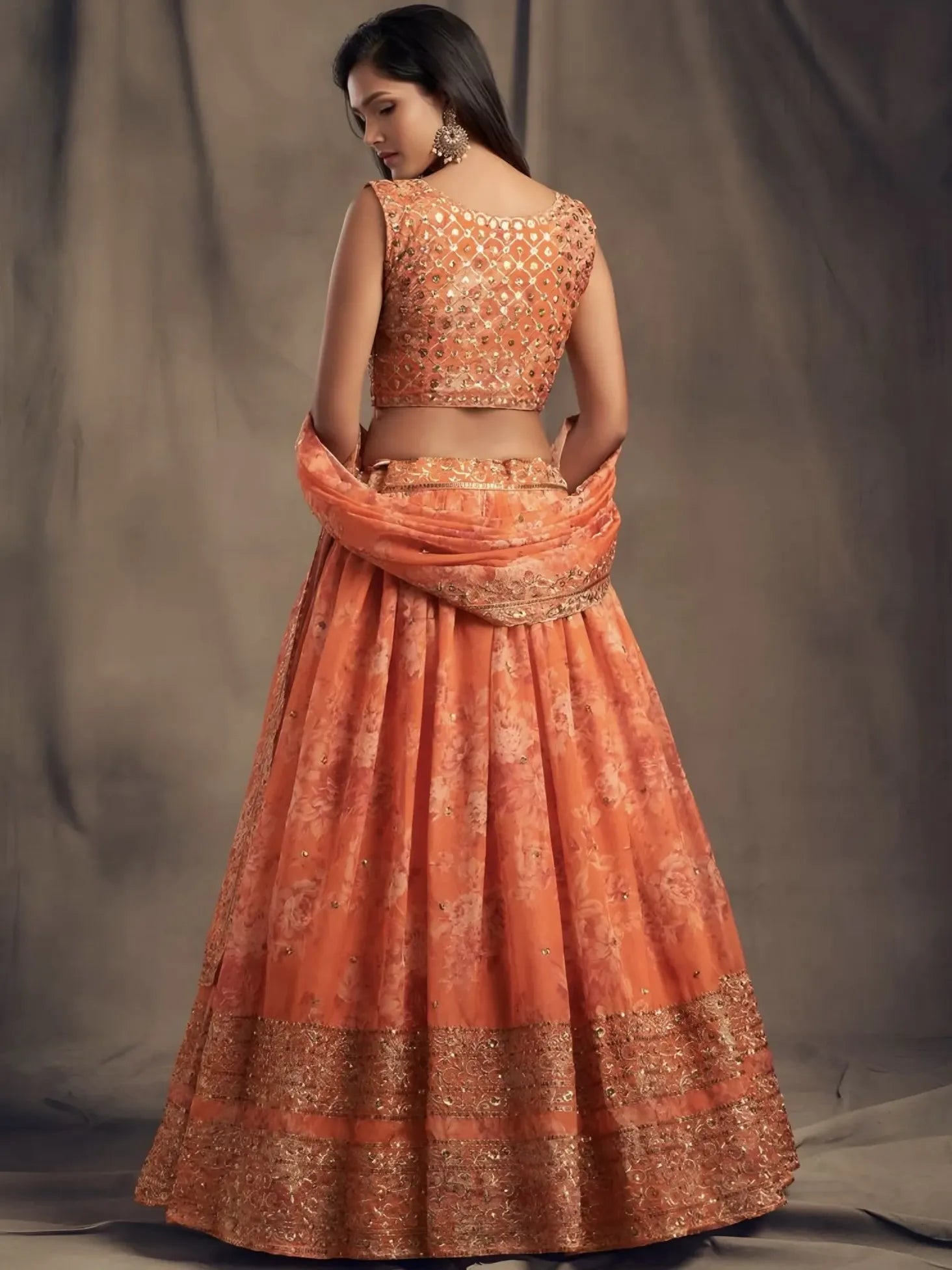 Woman wearing an orange traditional outfit with a plain background