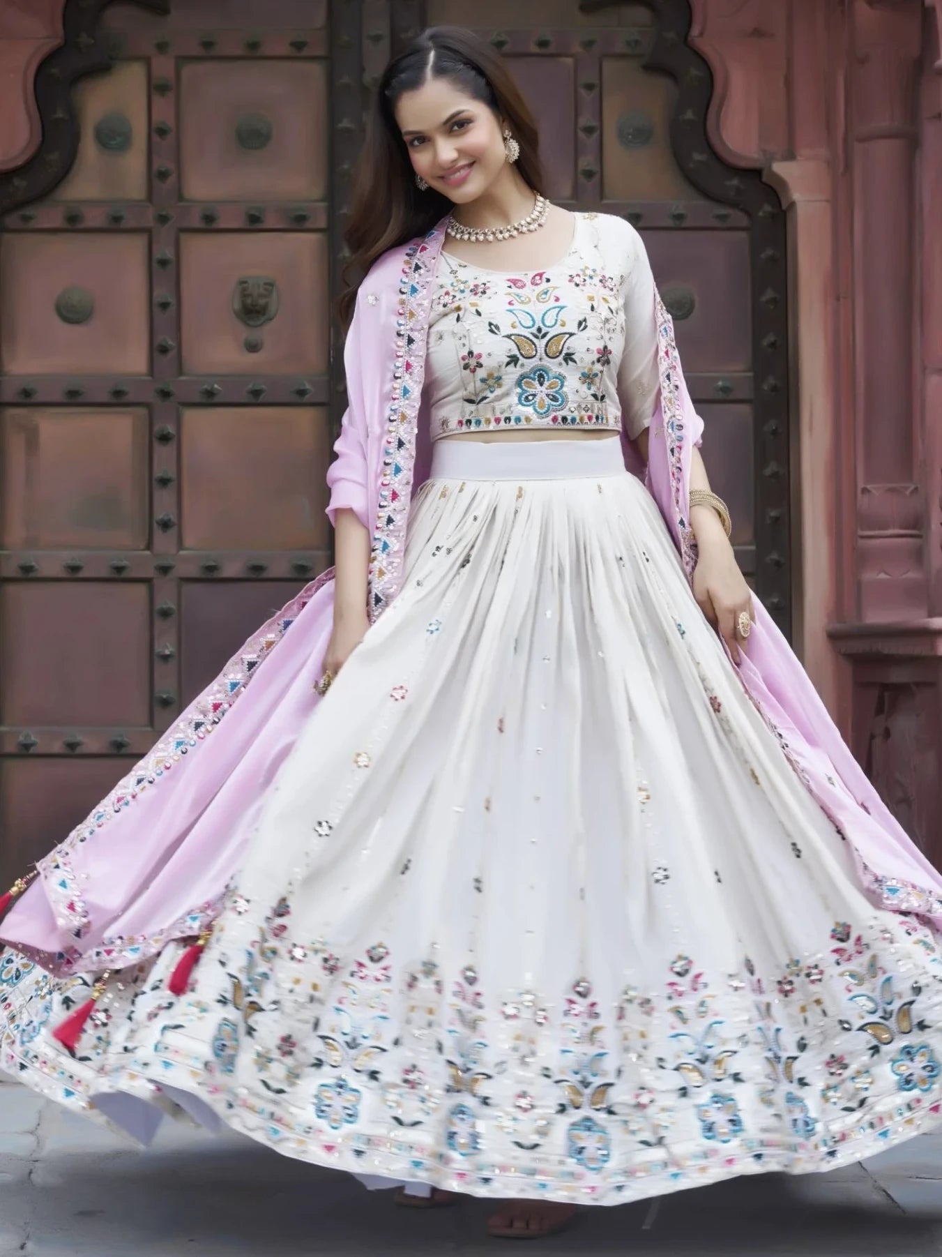 Woman in a traditional outfit with floral patterns in front of a textured wall.