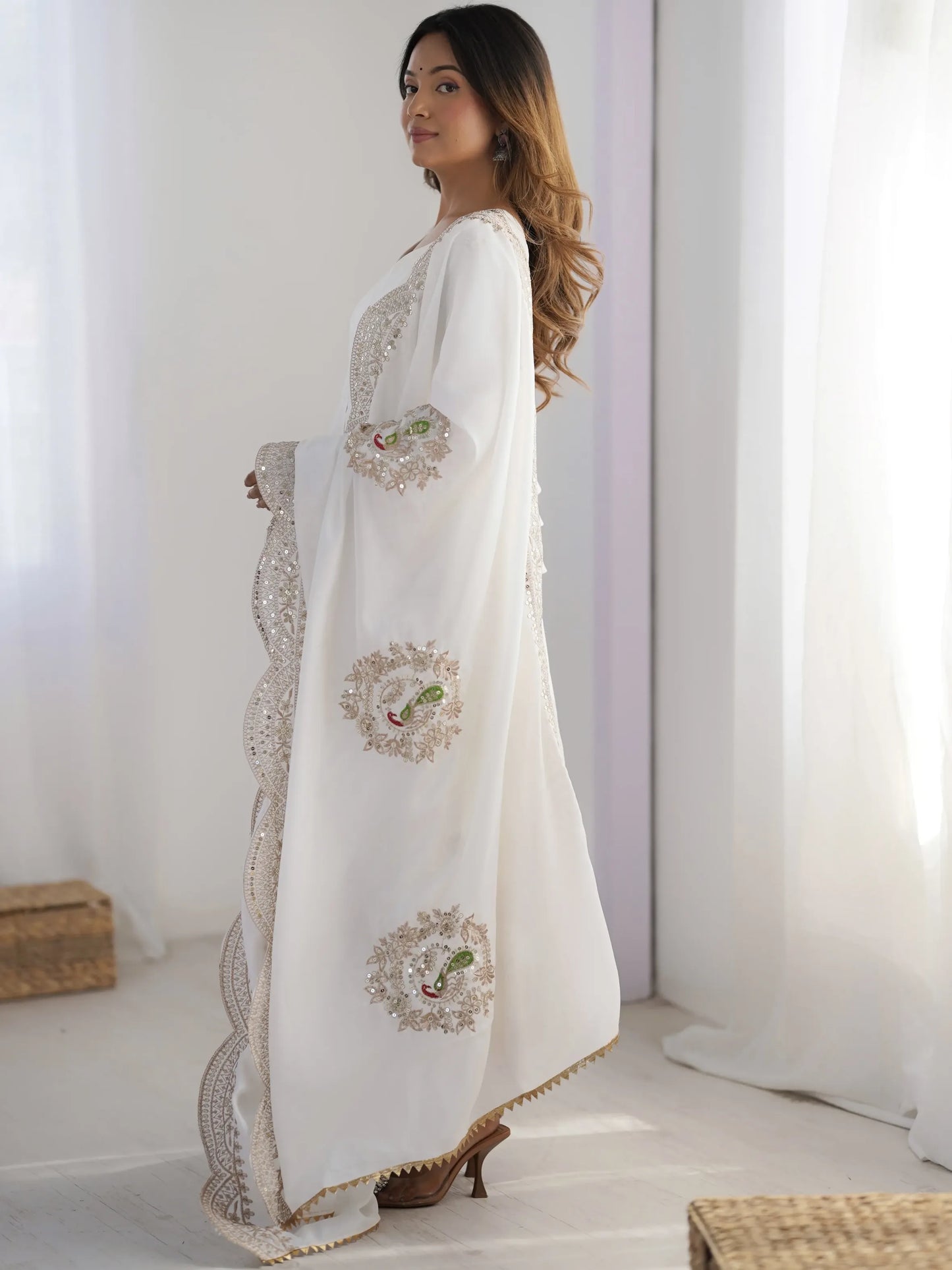Woman wearing a white embroidered dress in a bright room
