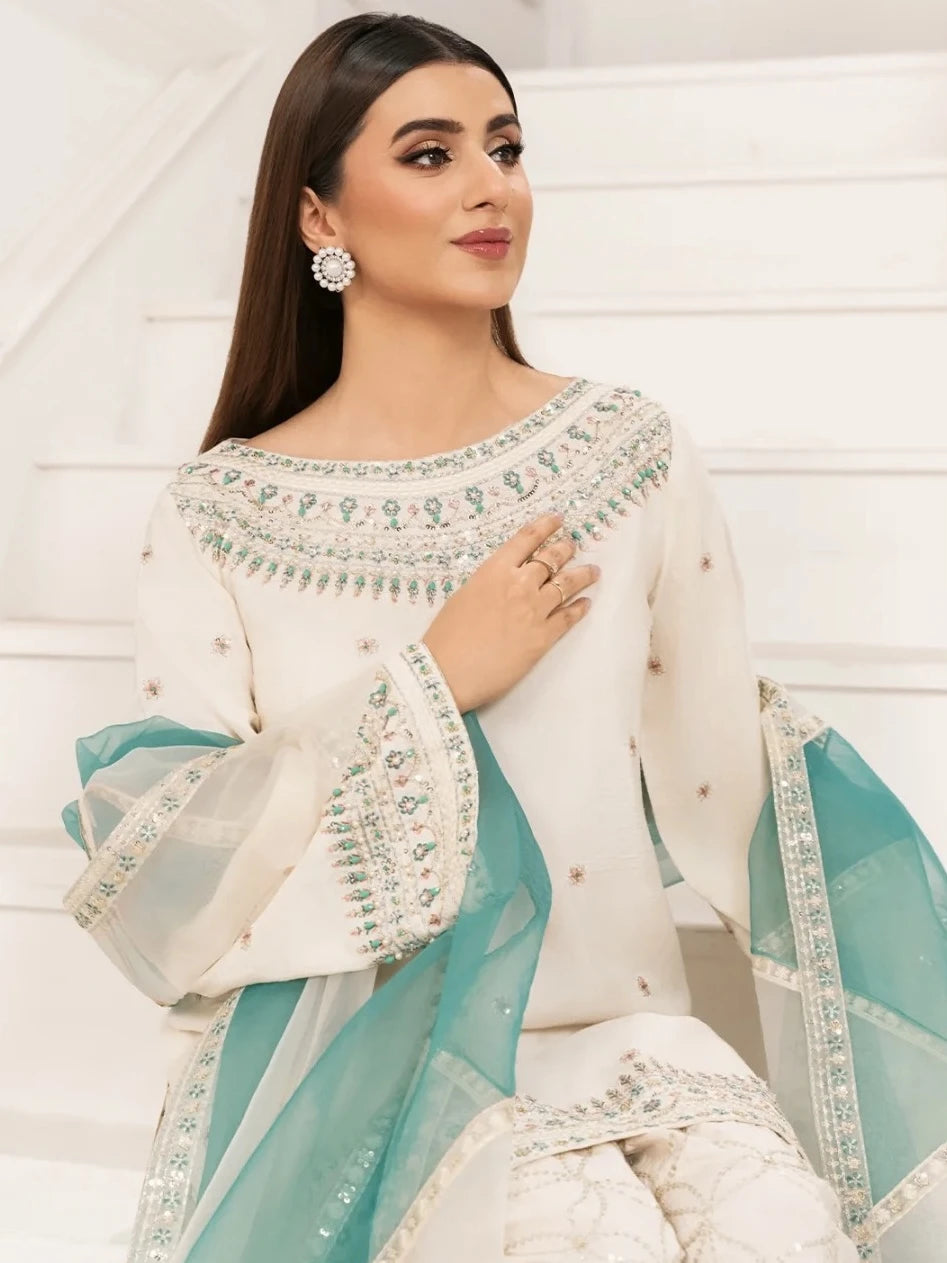 Woman wearing a white and teal embroidered saree with a white background