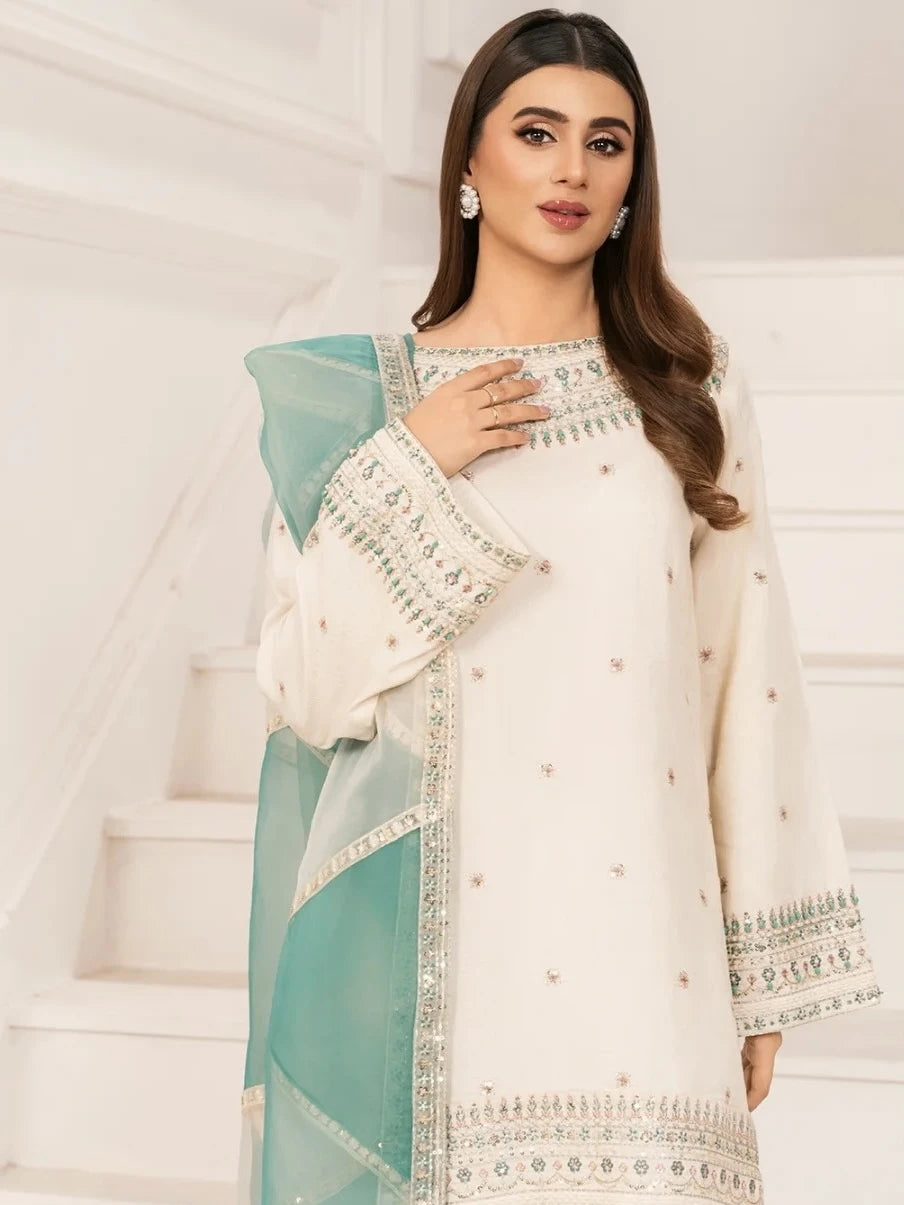 Woman wearing a white and teal traditional outfit with intricate patterns.