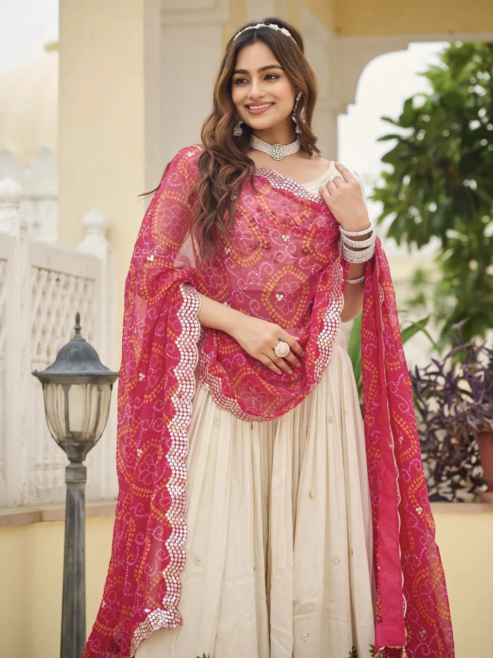 Woman wearing a pink and white traditional outfit with a matching dupatta outdoors.