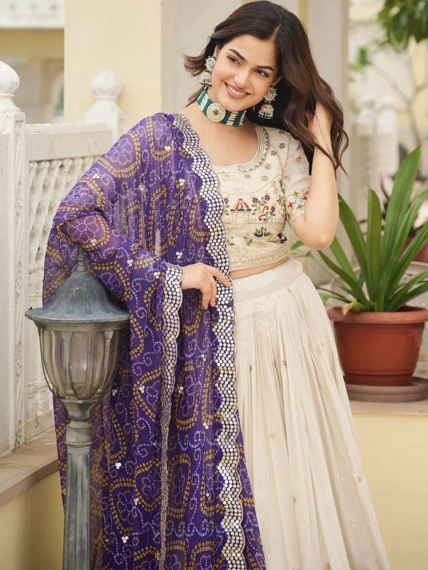 Woman wearing a purple and white traditional outfit with a plant and lamp post in the background