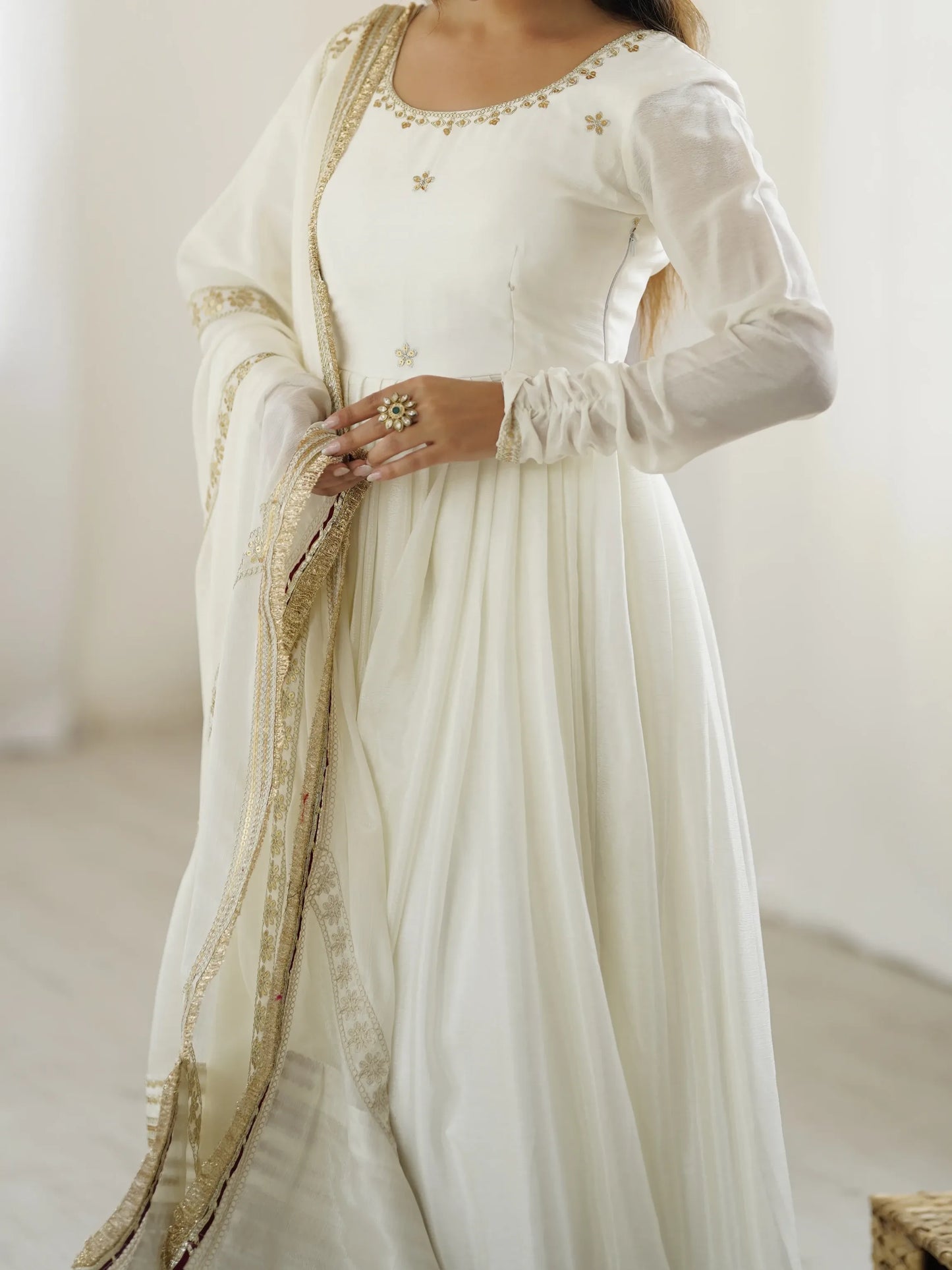 White dress with gold embroidery on a plain background
