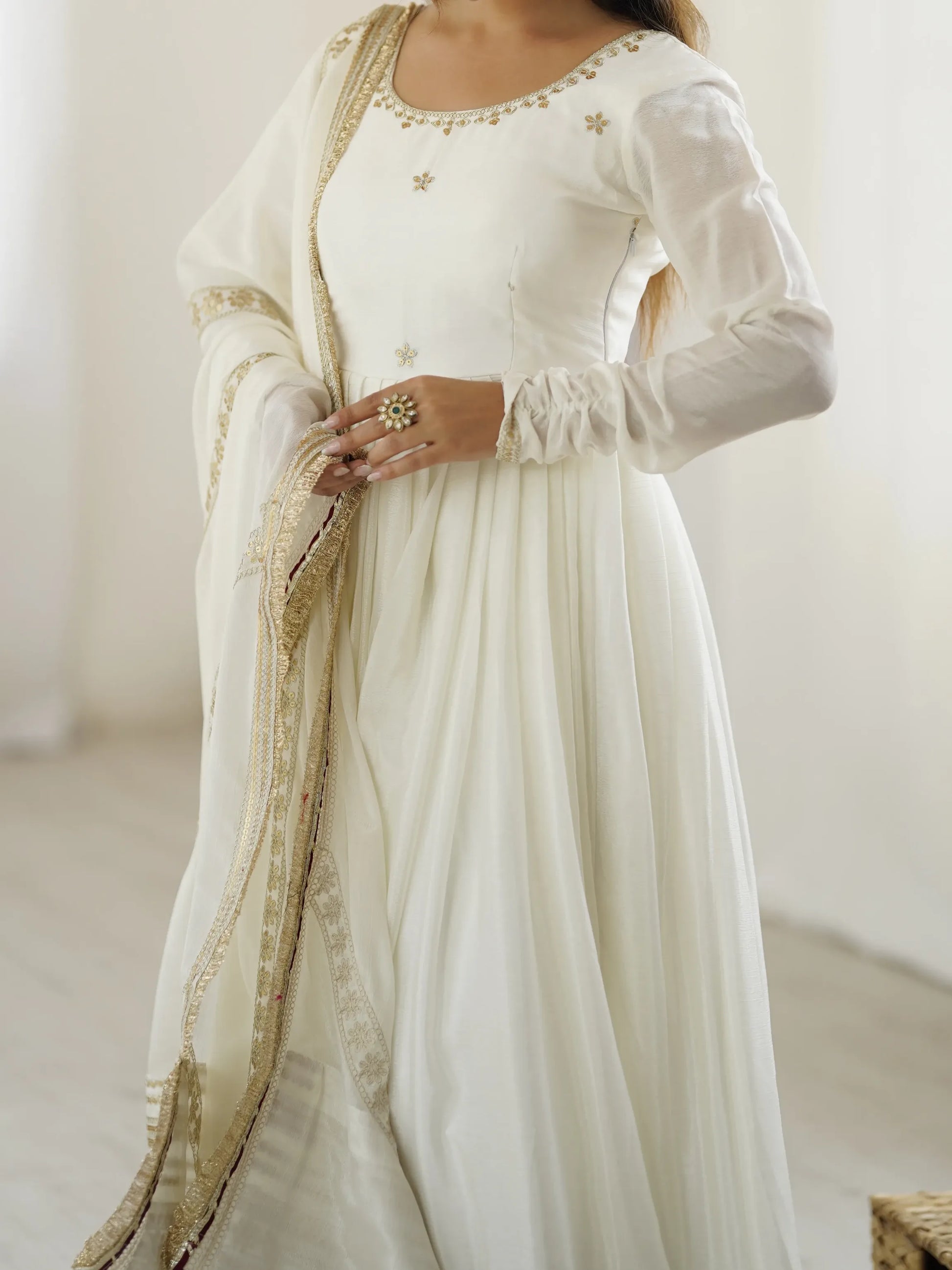 White dress with gold embroidery on a plain background