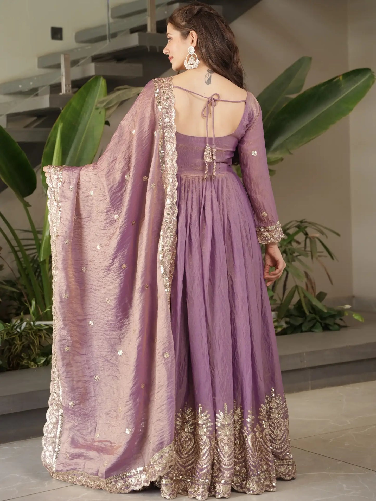 Woman wearing a purple embroidered dress with a matching dupatta in an indoor setting.