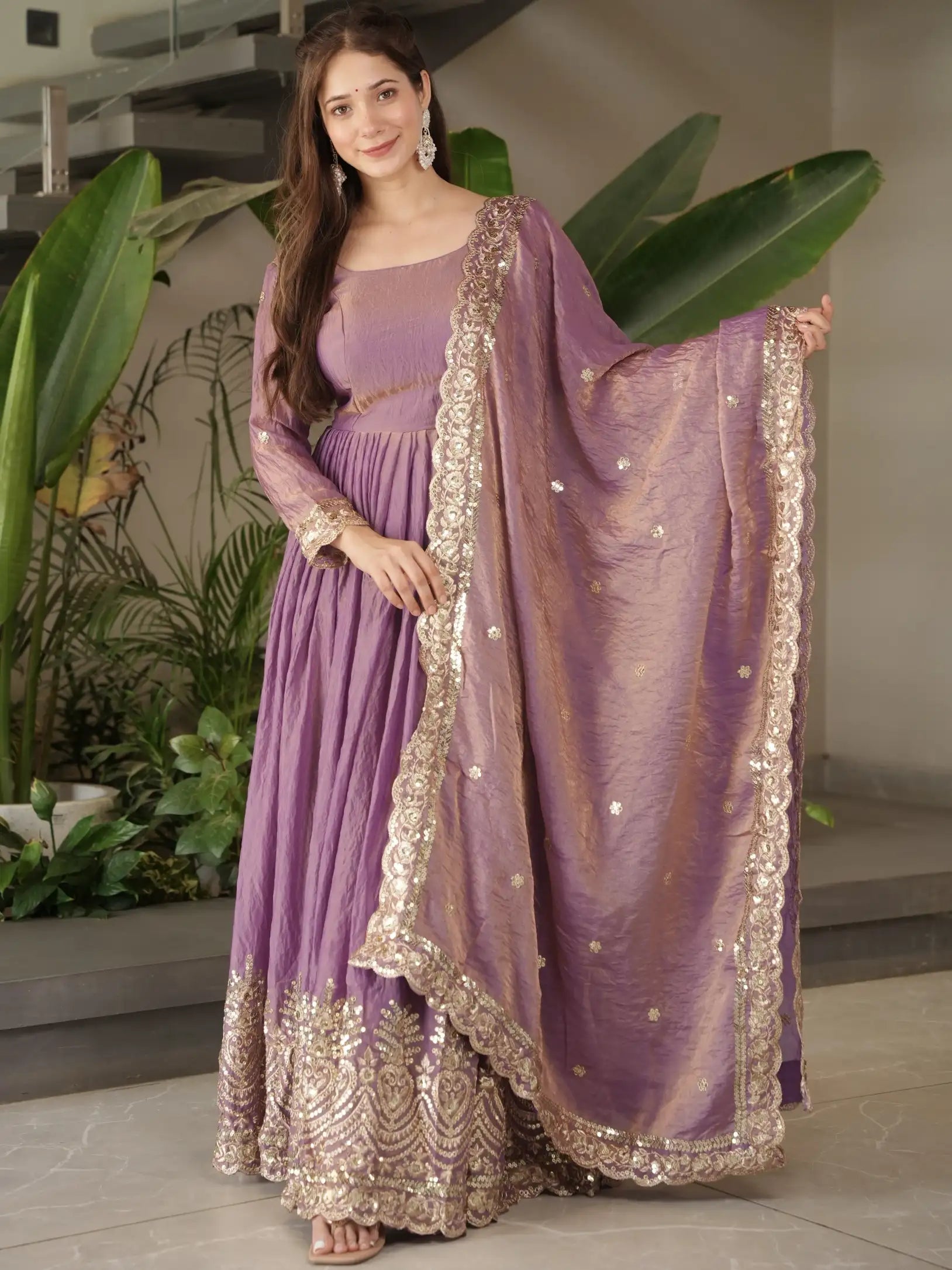 Woman wearing a purple traditional outfit with a matching dupatta in an indoor setting.