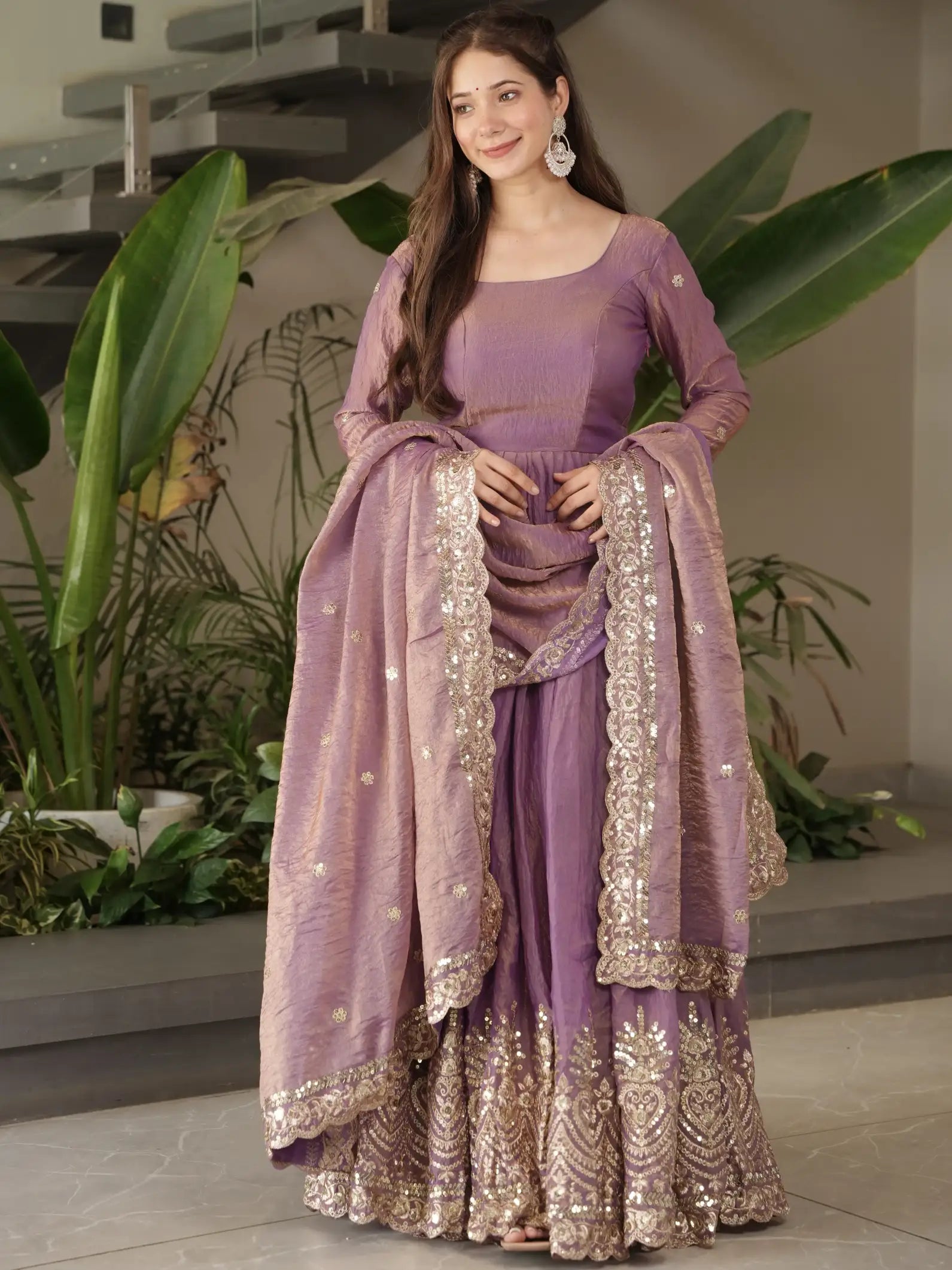 Woman wearing a purple traditional outfit with gold embroidery in an indoor setting.