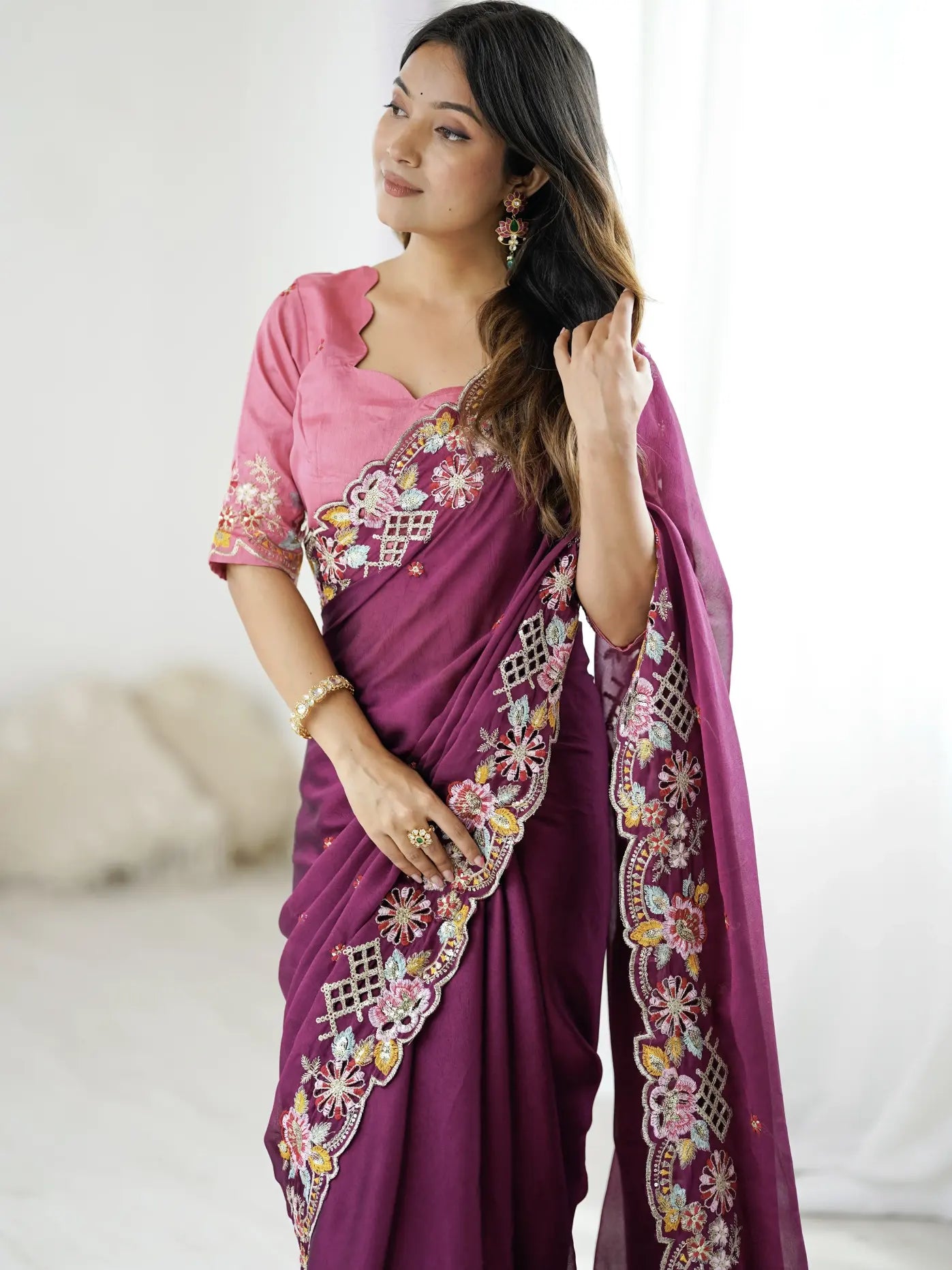 Woman wearing a purple saree with pink blouse against a white background