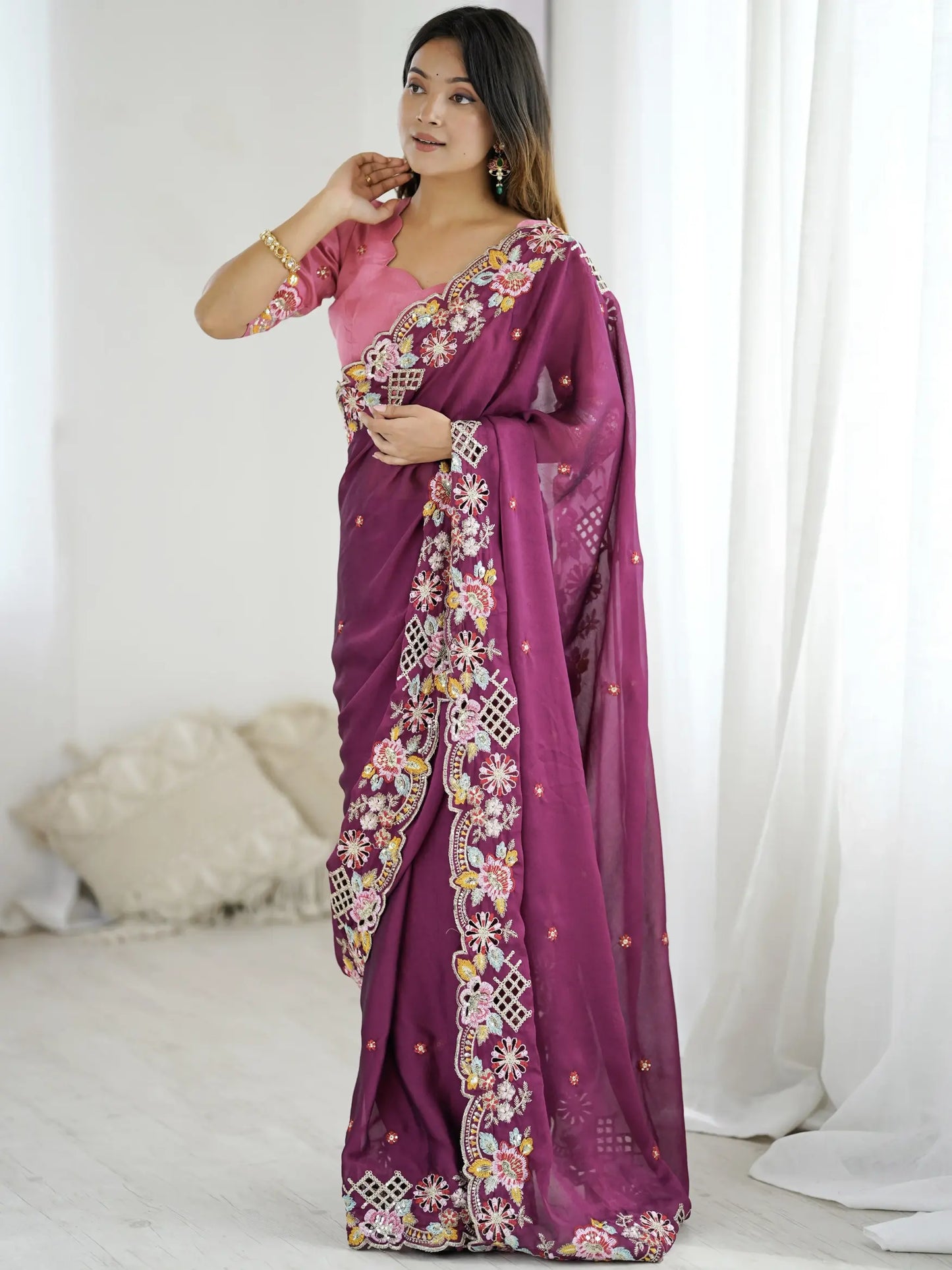 Woman wearing a purple saree with floral patterns on a white background