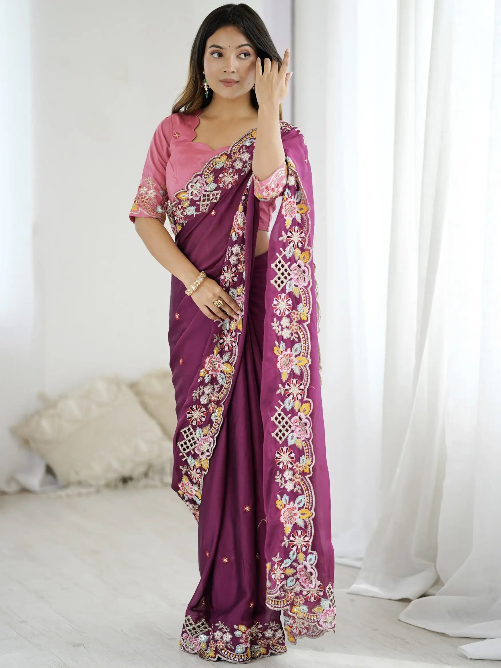 Woman wearing a purple saree with floral patterns in a minimalistic setting