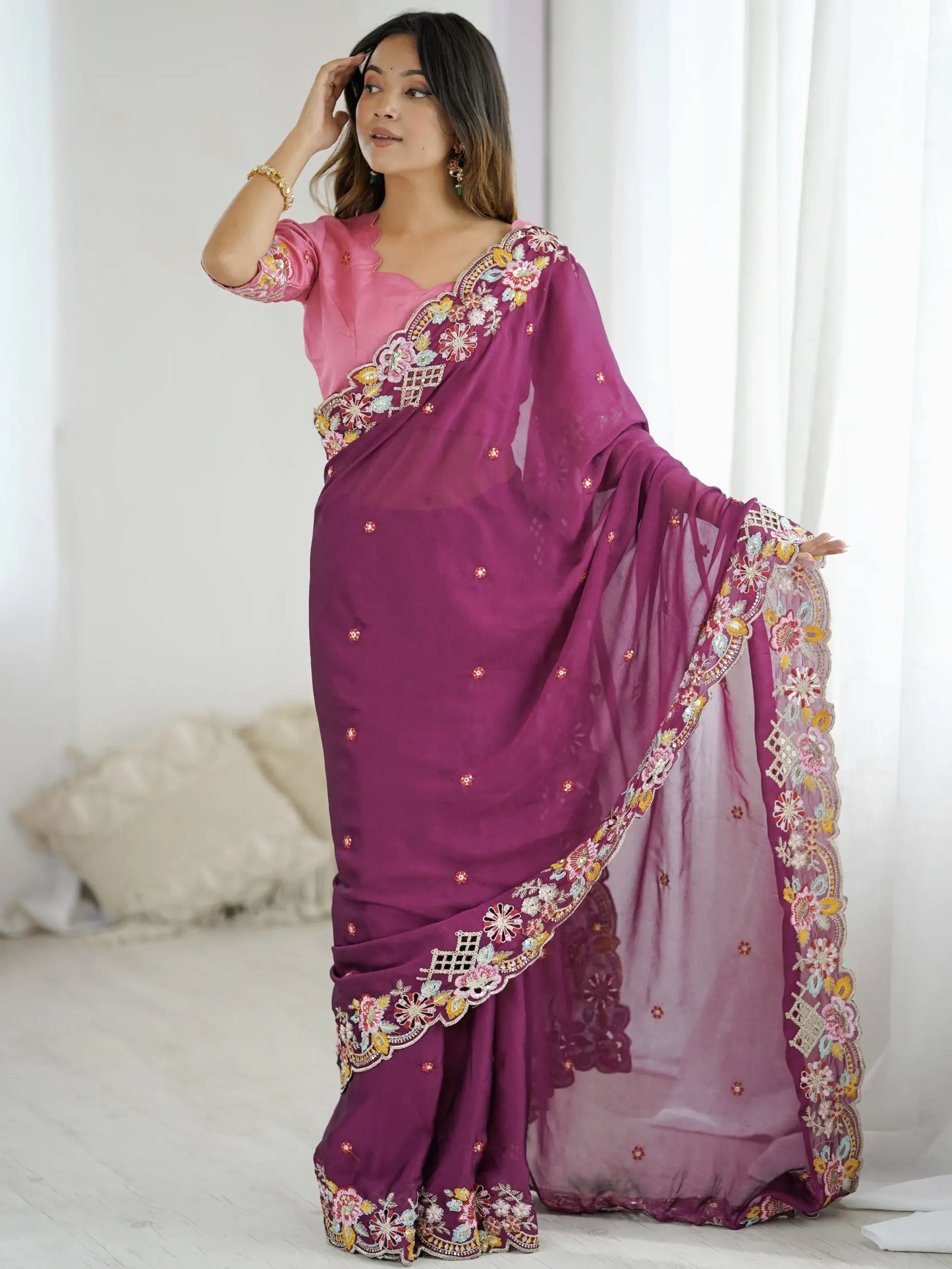 Woman wearing a purple saree with floral patterns in a room.