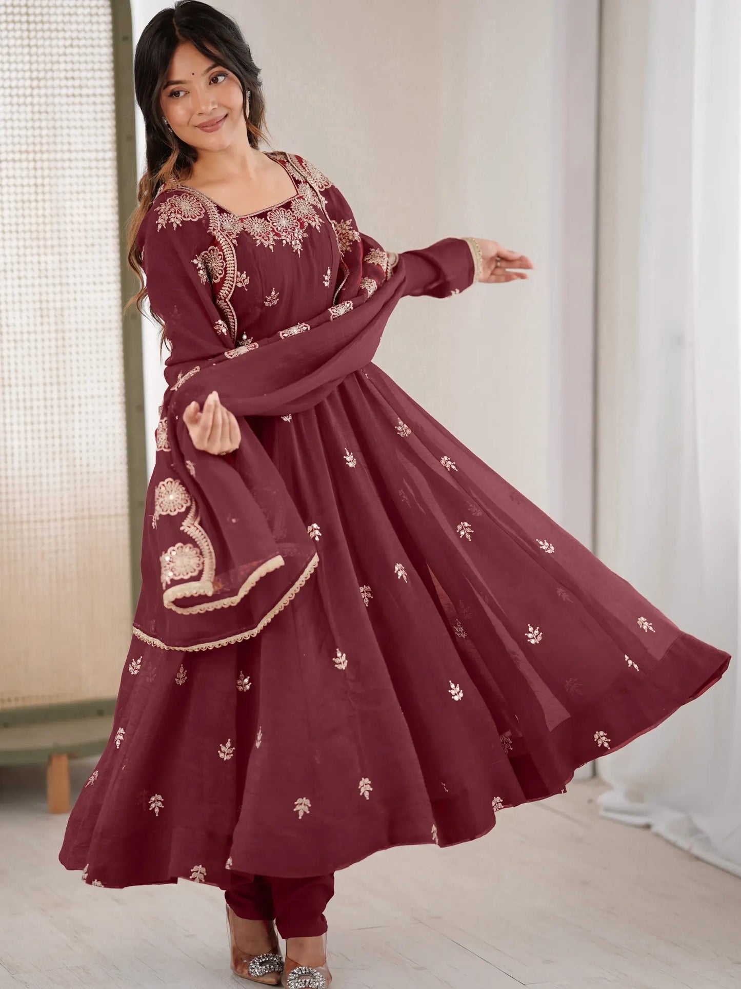 Woman wearing a maroon embroidered dress in a well-lit room.