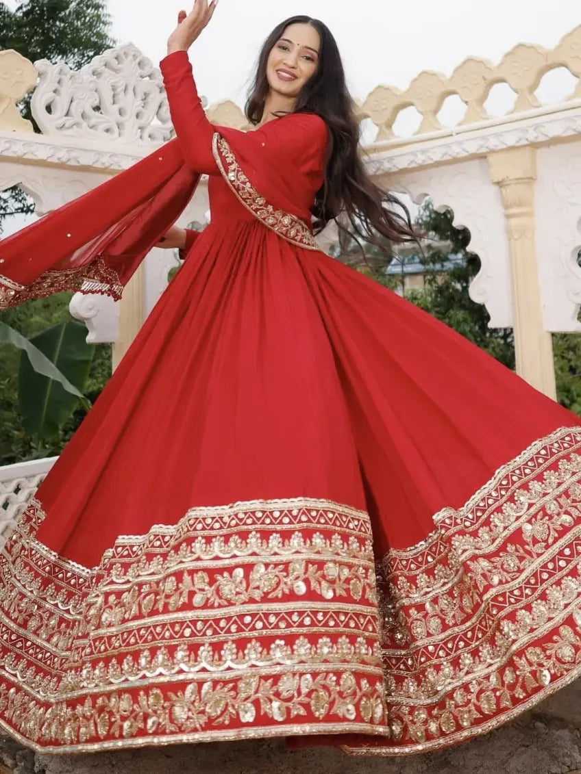 Woman in a red traditional outfit with gold embroidery against an architectural background