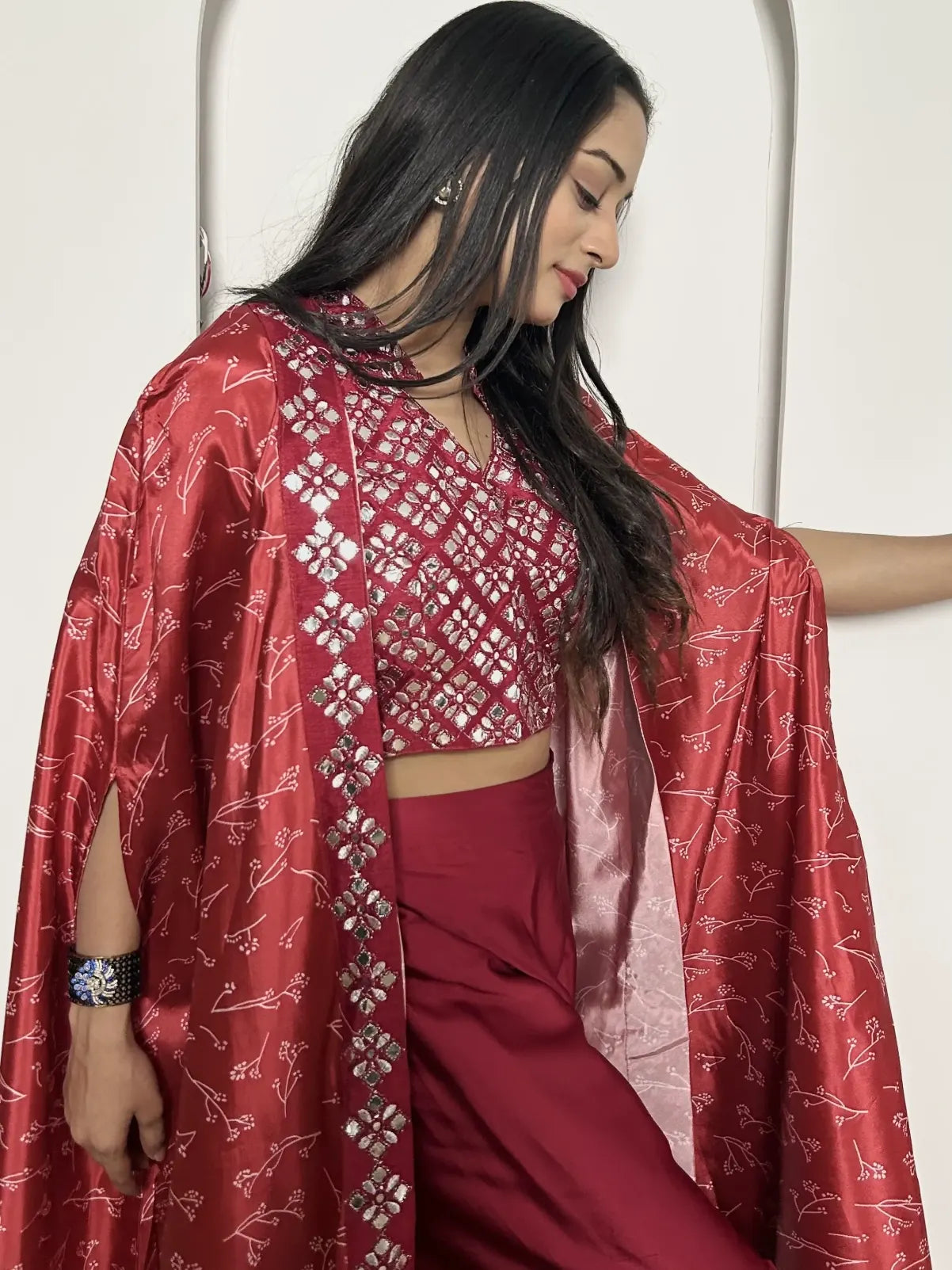 Woman wearing a red traditional outfit with a patterned shawl against a white background