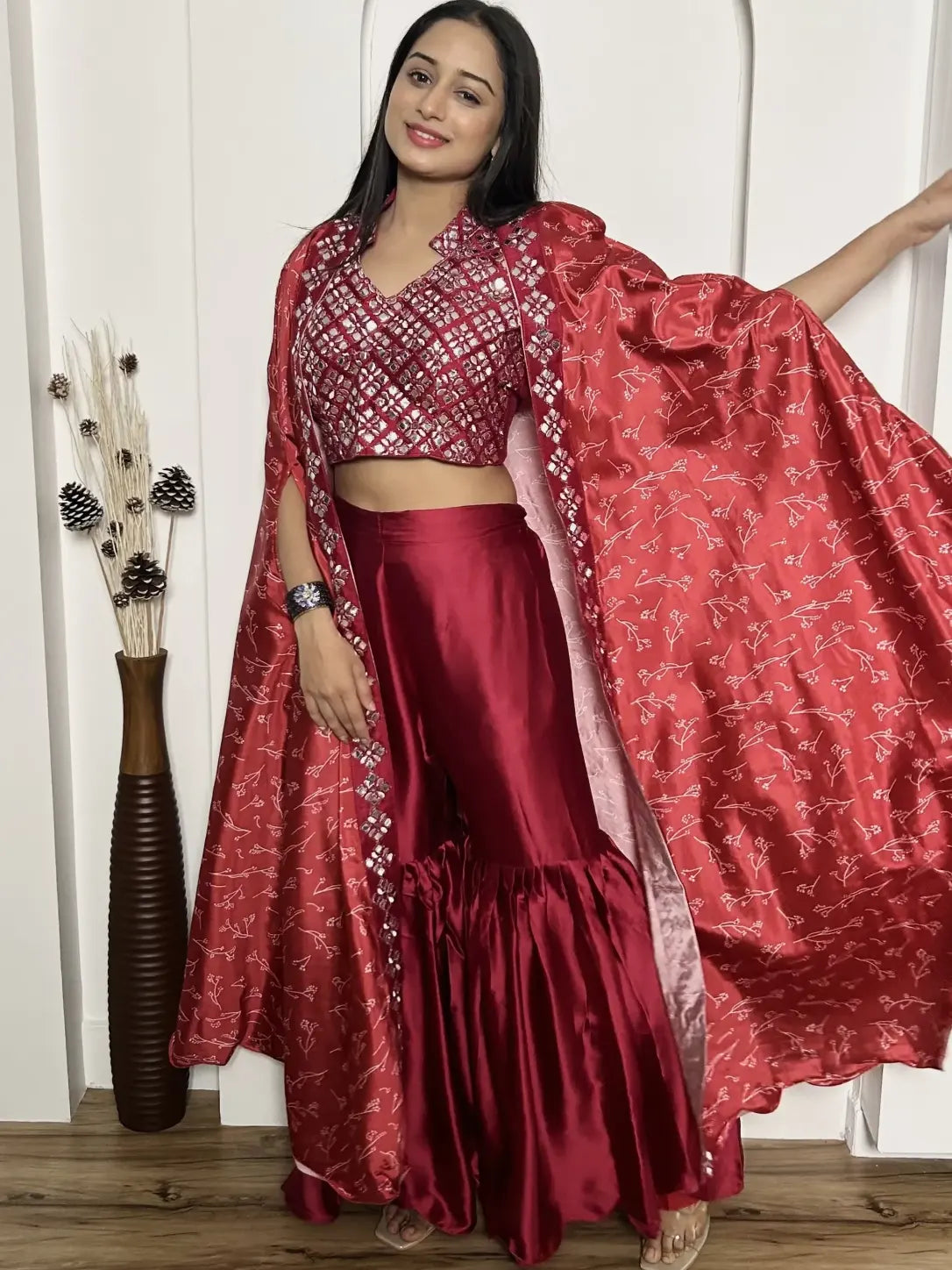 Woman wearing a red traditional outfit with a matching dupatta, standing indoors.