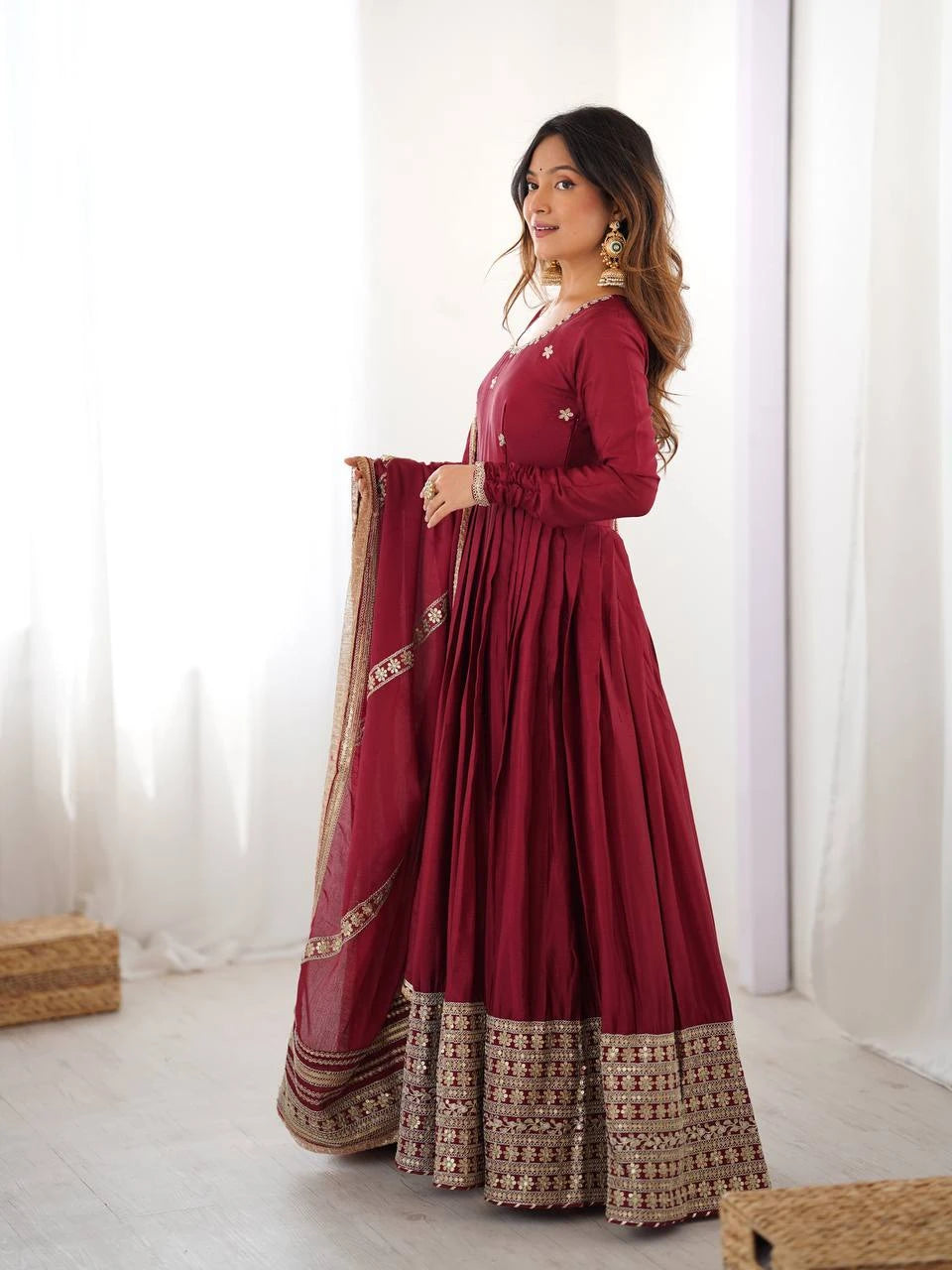 Woman in a red traditional outfit with gold details against a white background